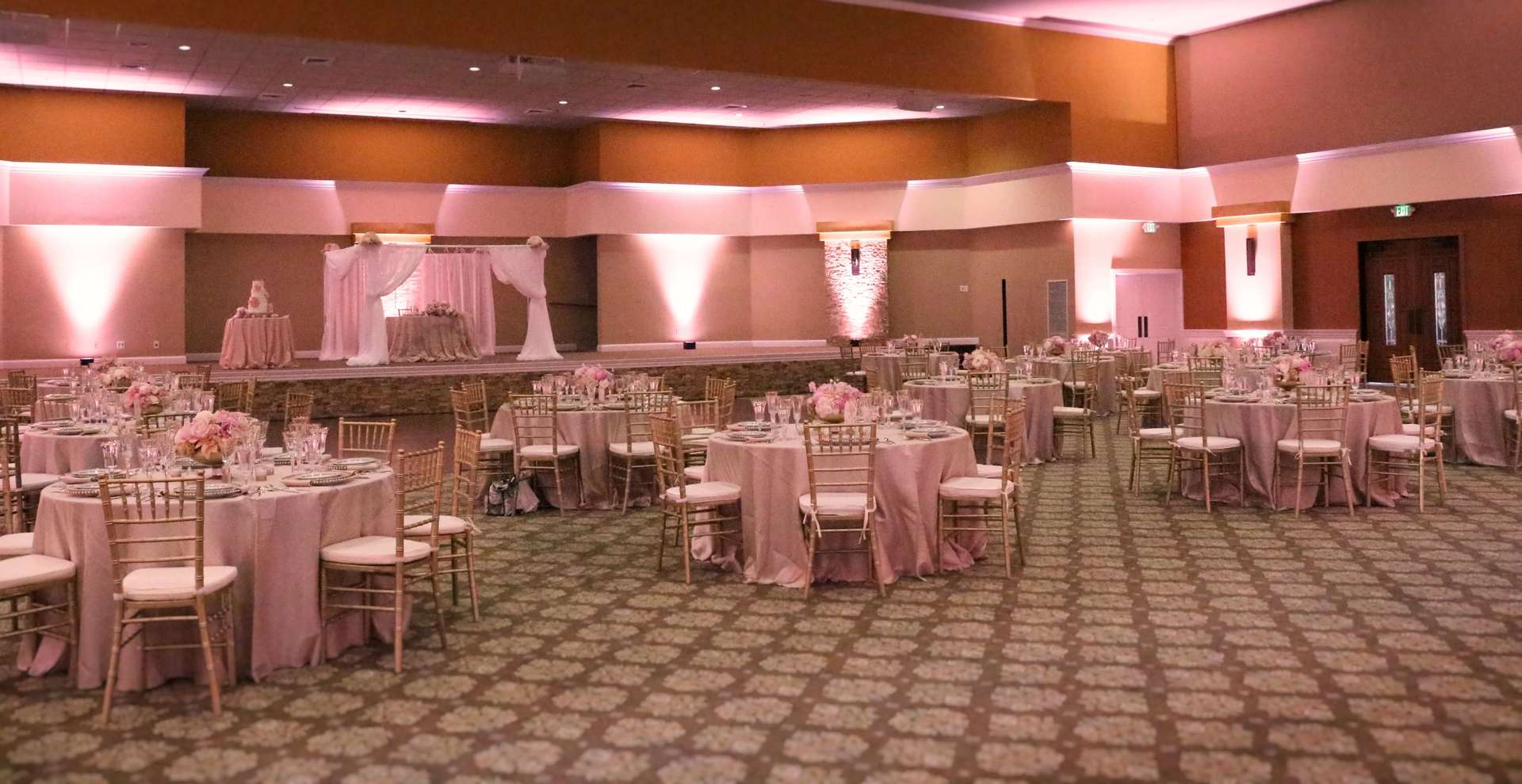 A large room with tables and chairs set up for a wedding reception.