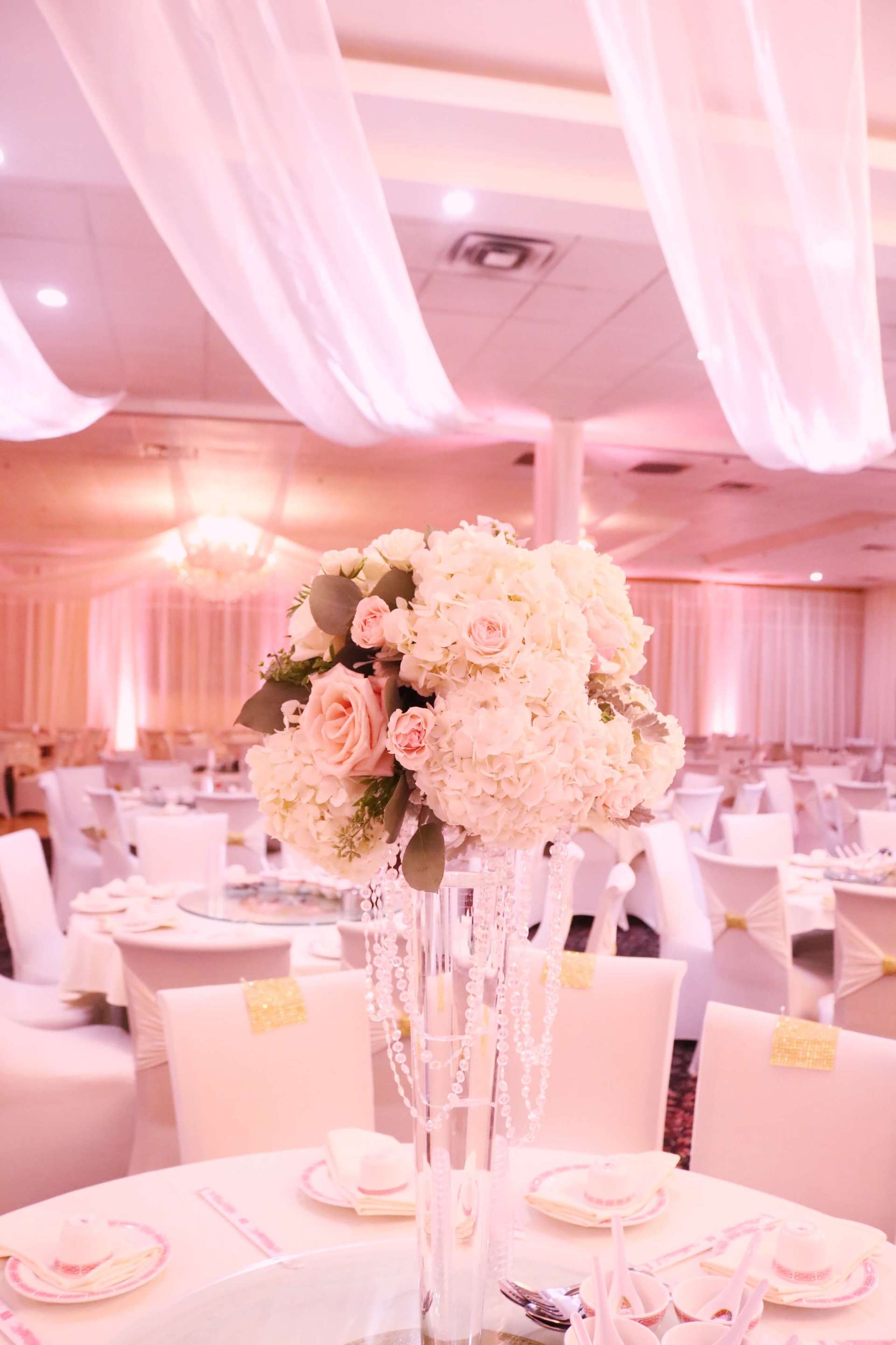 A tall vase filled with flowers is sitting on a table in a large room.