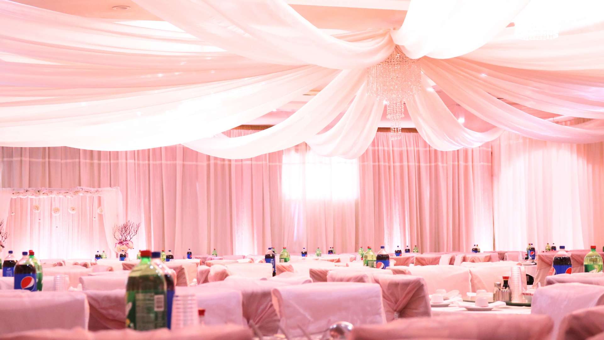 A large room with tables and chairs and a pink curtain hanging from the ceiling.