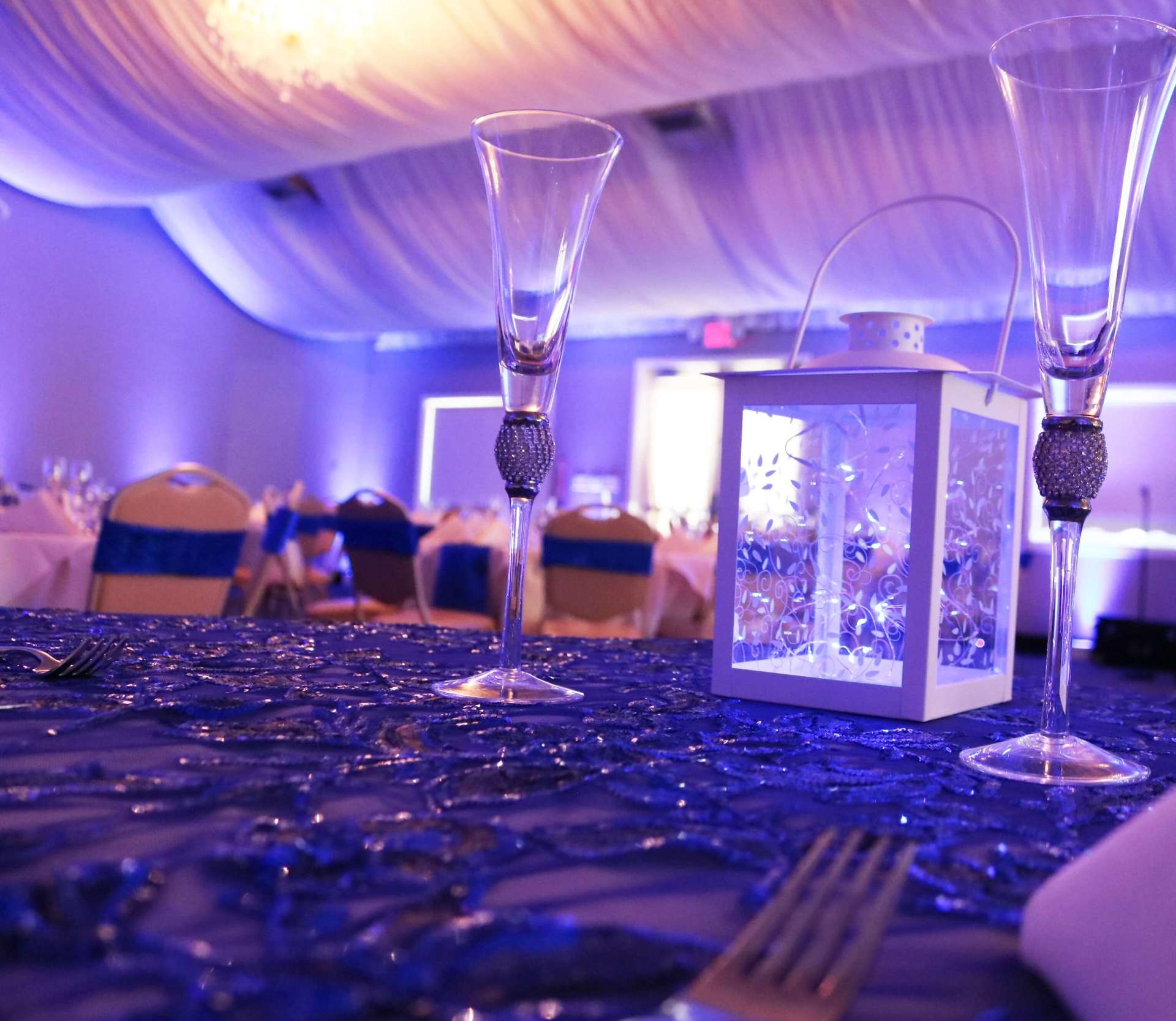 A lantern sits on a table next to two wine glasses