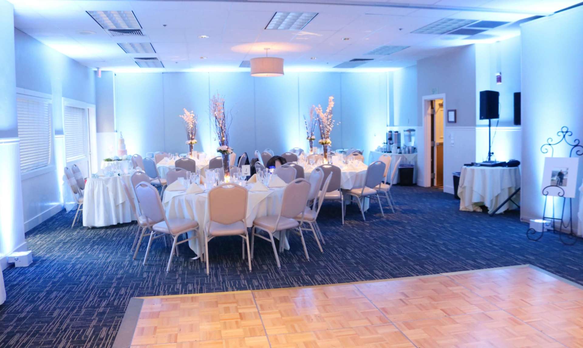 A large room with tables and chairs set up for a wedding reception.