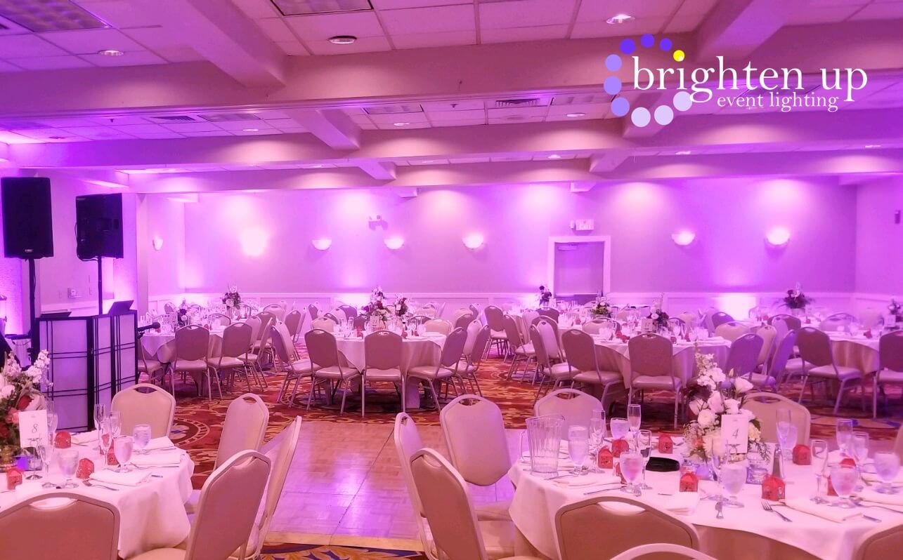 A large room filled with tables and chairs and purple lights.