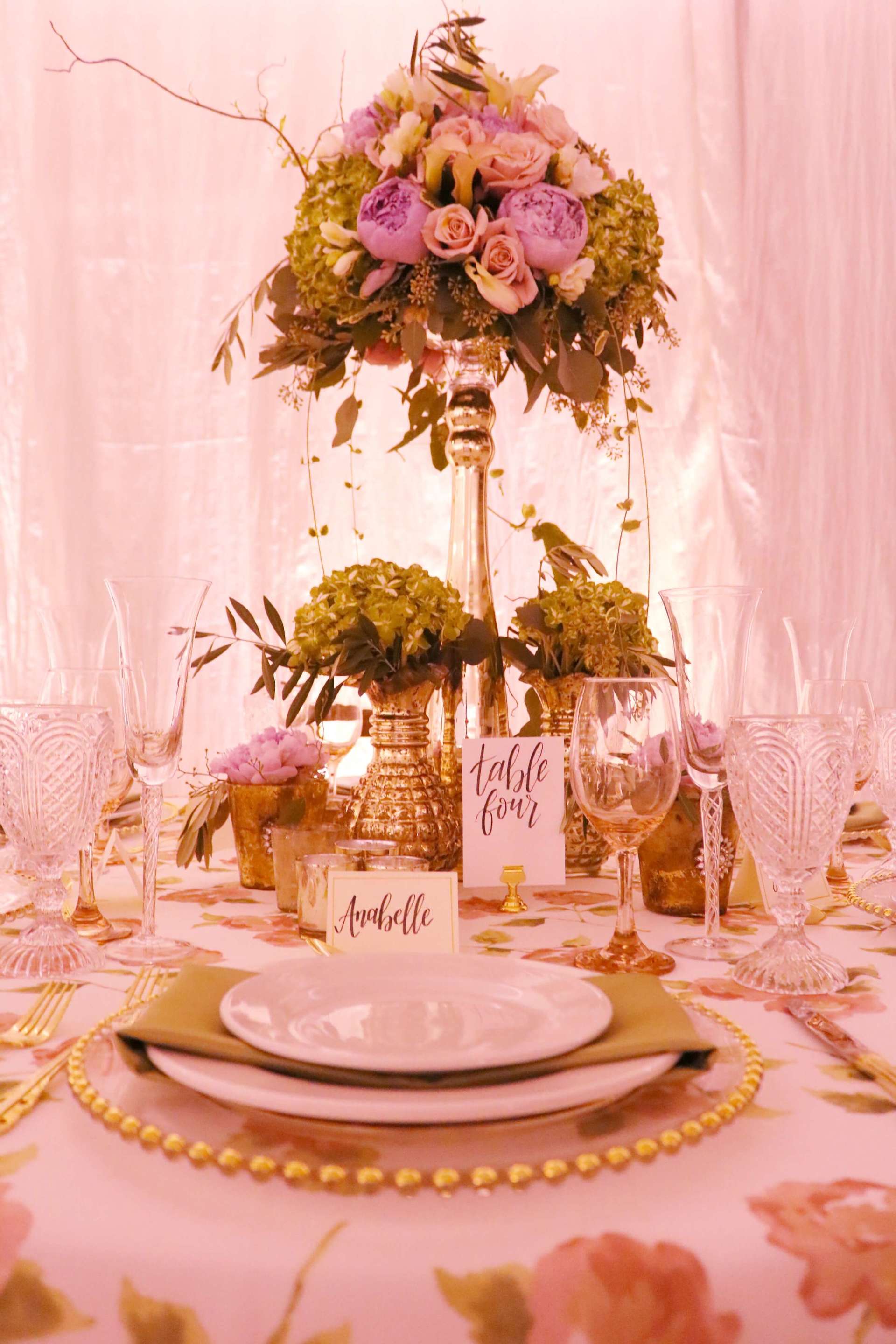 A table with plates , glasses , and a vase of flowers on it.
