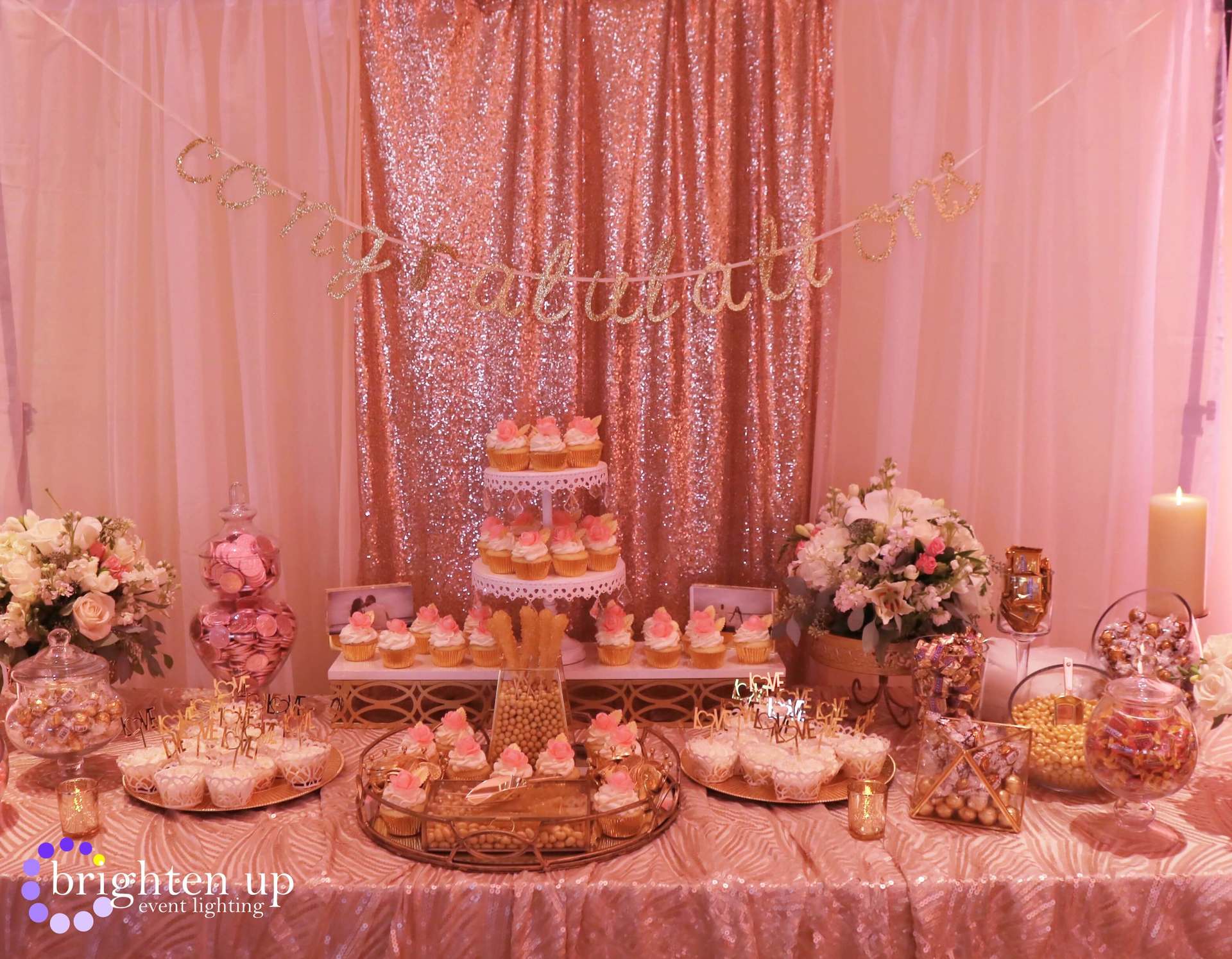 A table with cupcakes , candy , and flowers on it.