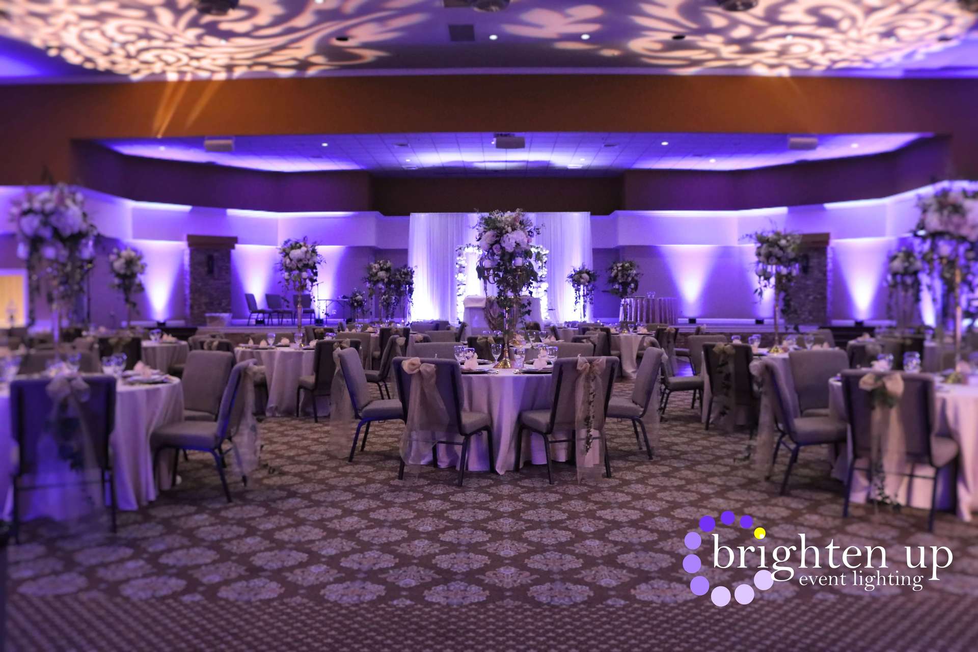 A large room with tables and chairs set up for a wedding reception.