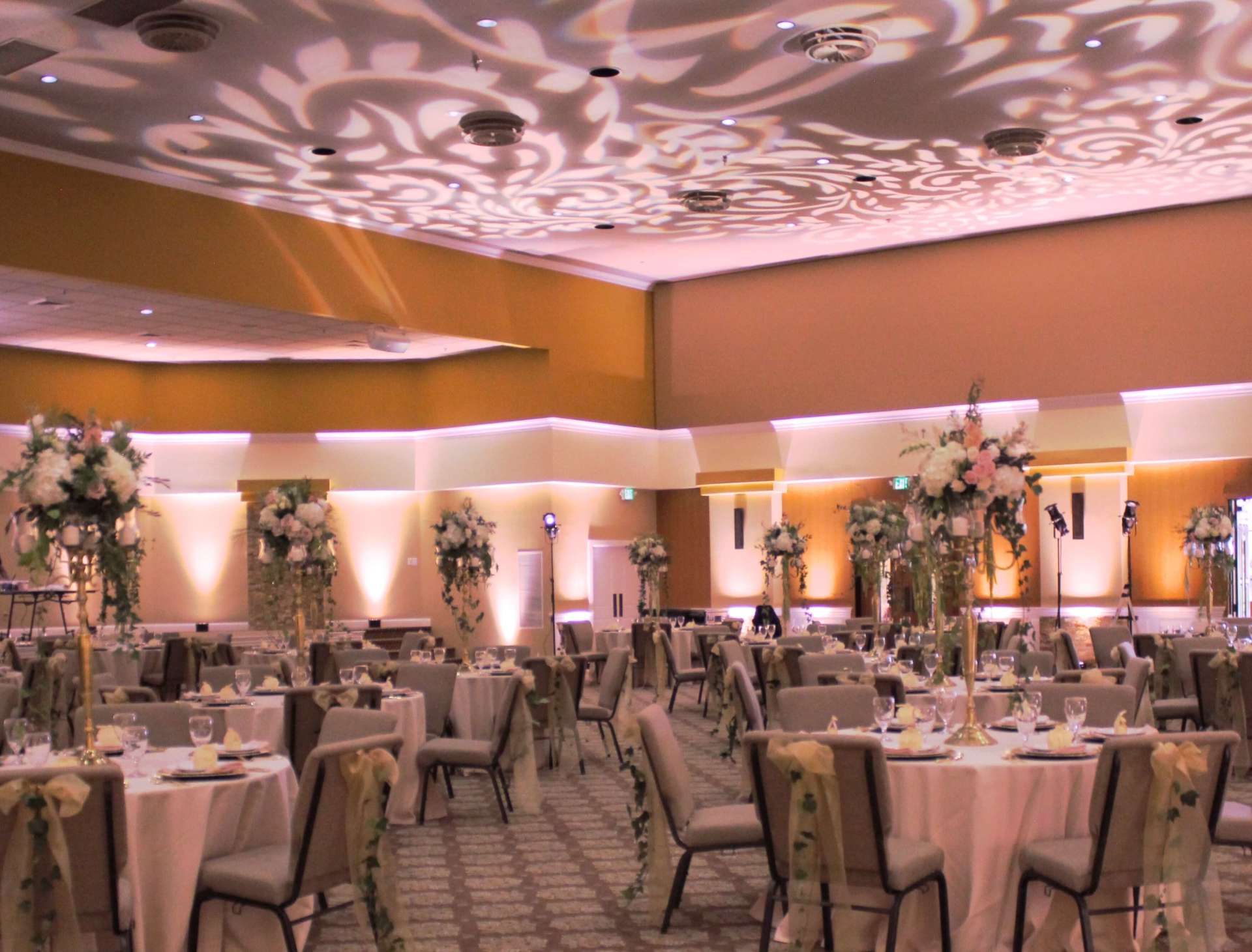 A large room with tables and chairs set up for a wedding reception