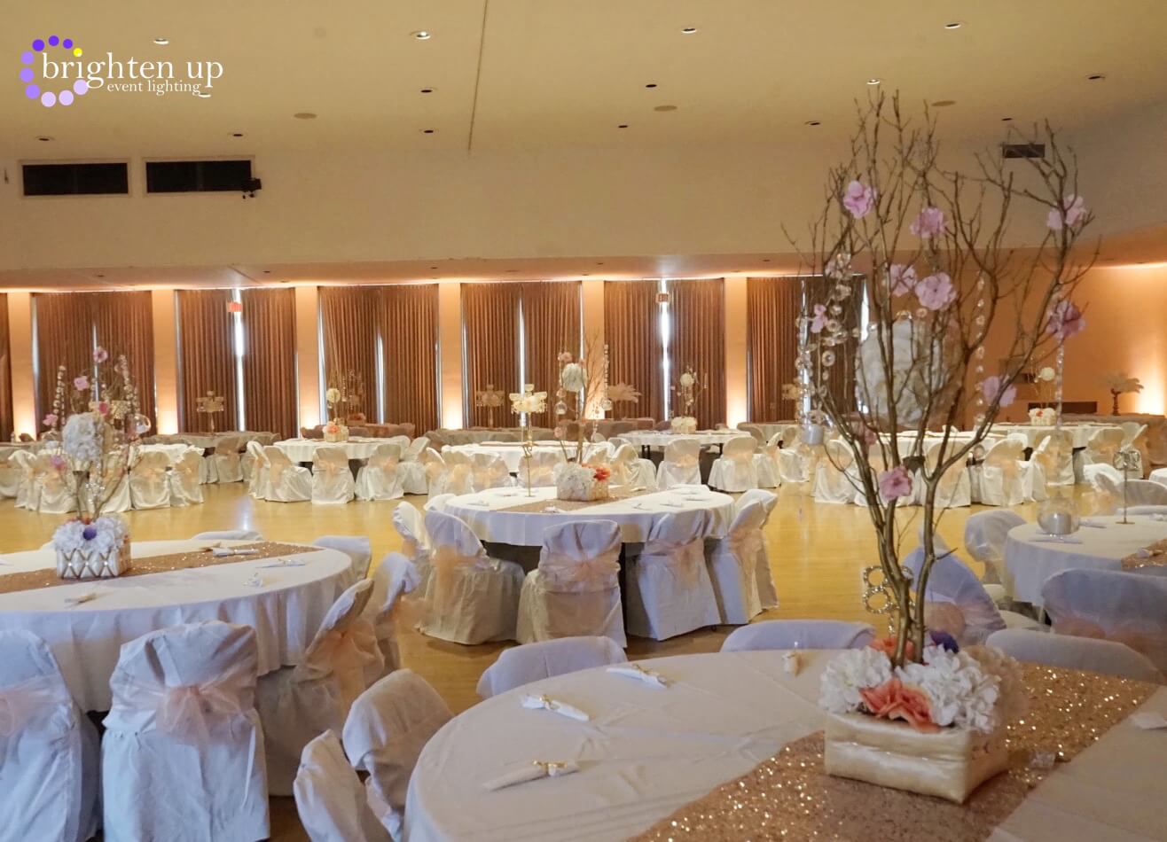 A large room with tables and chairs set up for a wedding reception.