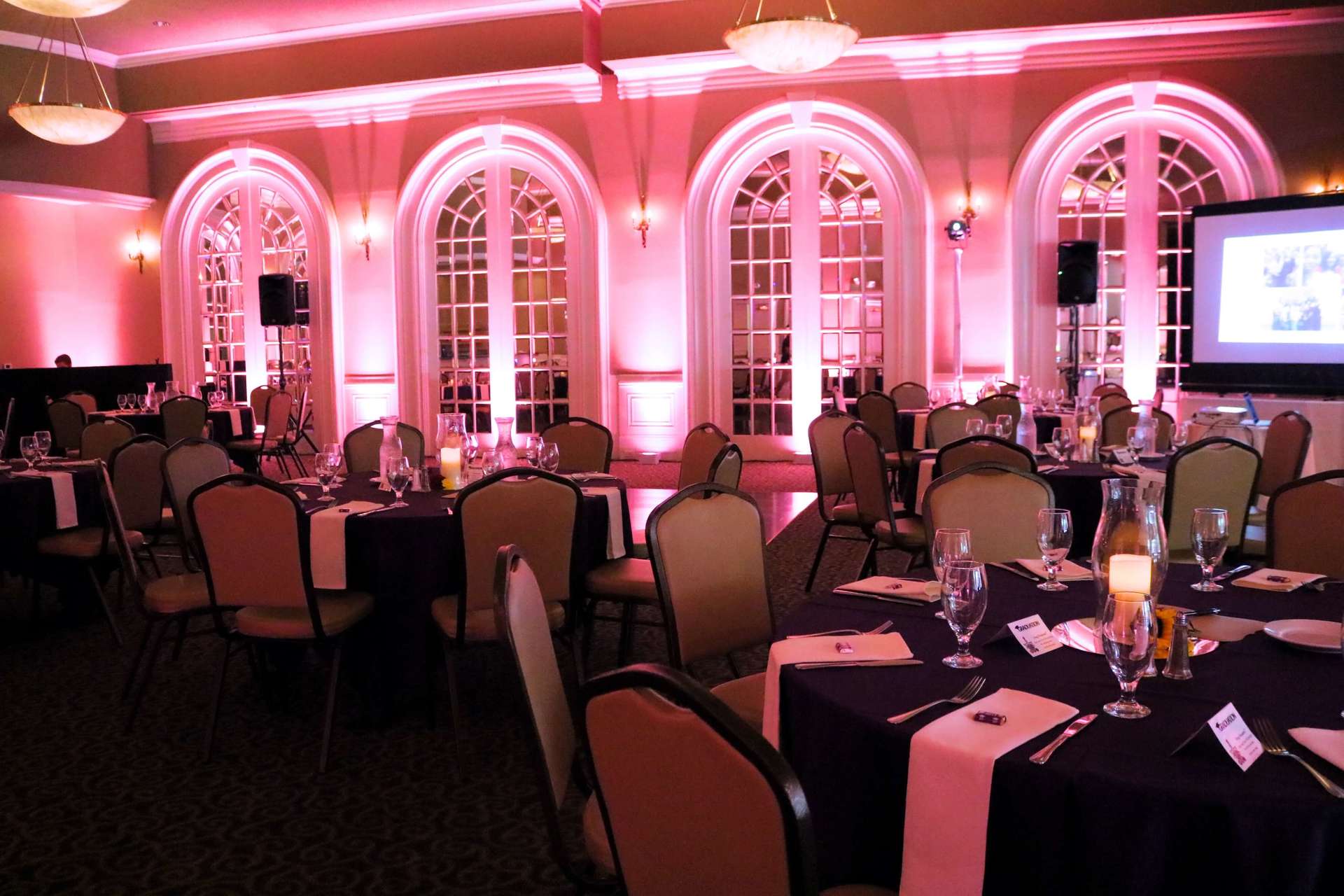 A large room filled with tables and chairs with pink lights on the walls
