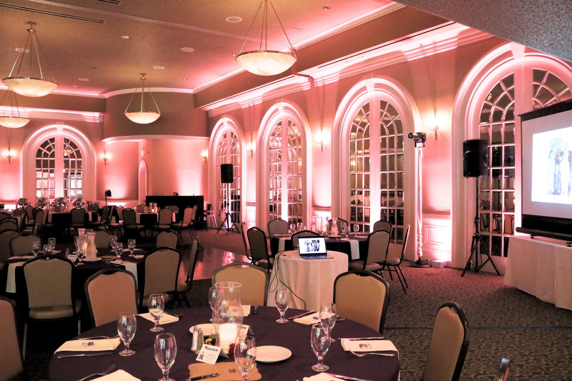 A large room with tables and chairs and a projector screen