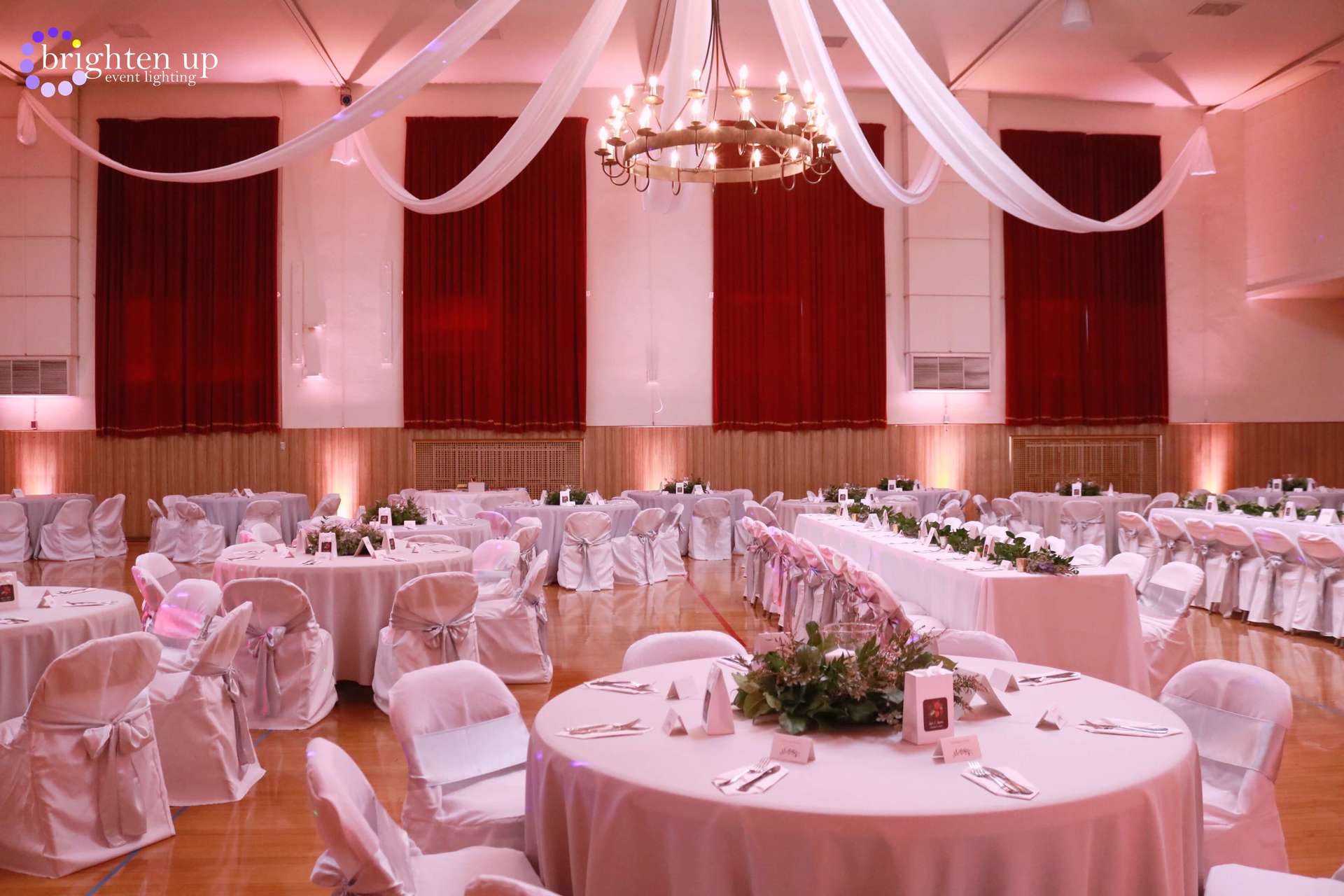 A large room with tables and chairs set up for a wedding reception.