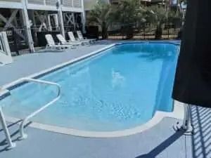 A large swimming pool surrounded by chairs and umbrellas.