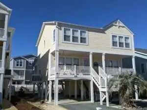 A large yellow house with a lot of windows is sitting on top of stilts.