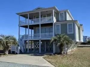 A large house with a lot of windows and balconies is sitting on top of a dirt field.