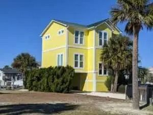 A yellow house with a palm tree in front of it.