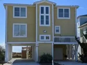 A large yellow house with a lot of windows on a sunny day.