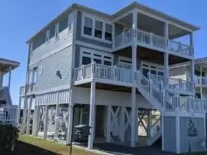 A large white house with stairs leading up to the second floor.