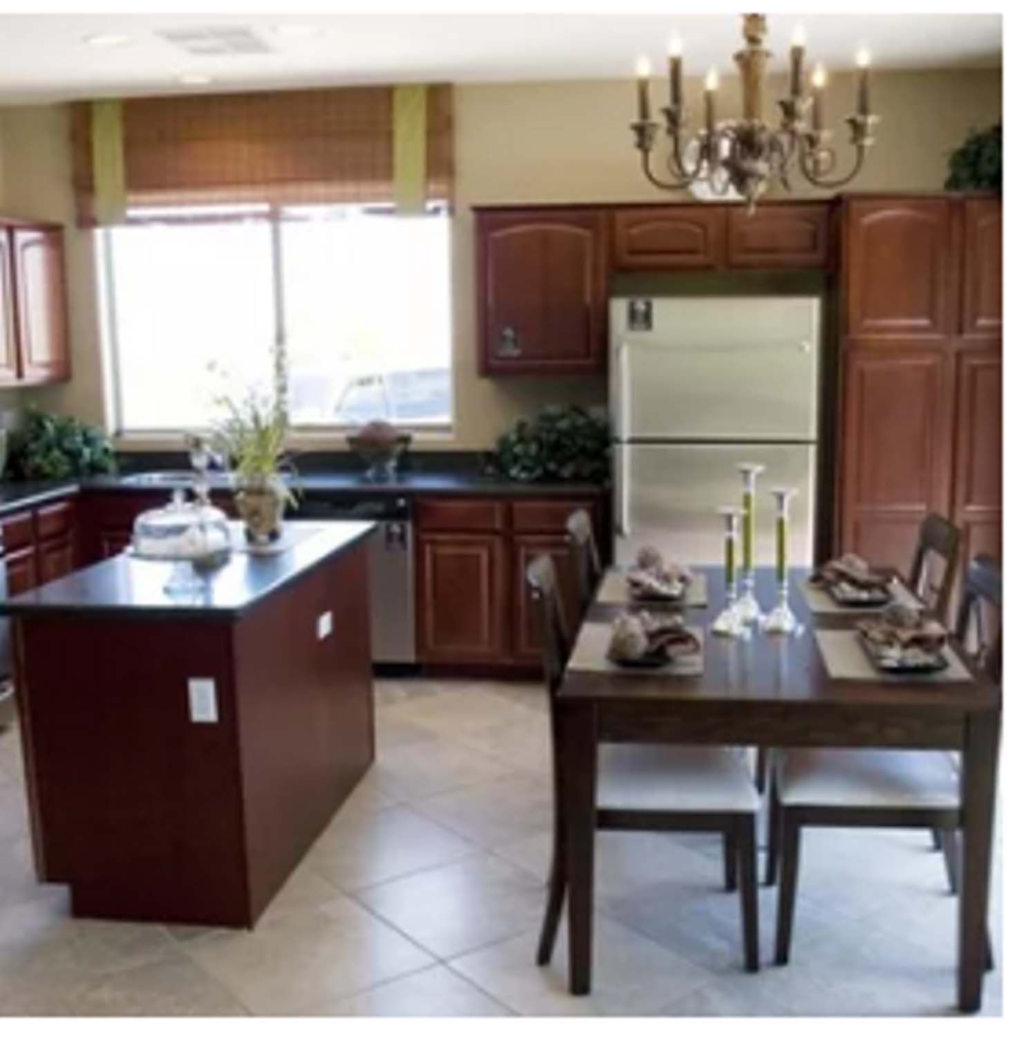 Kitchen with dark cabinetry, stainless steel appliances, an island, and a dining table set for a meal.