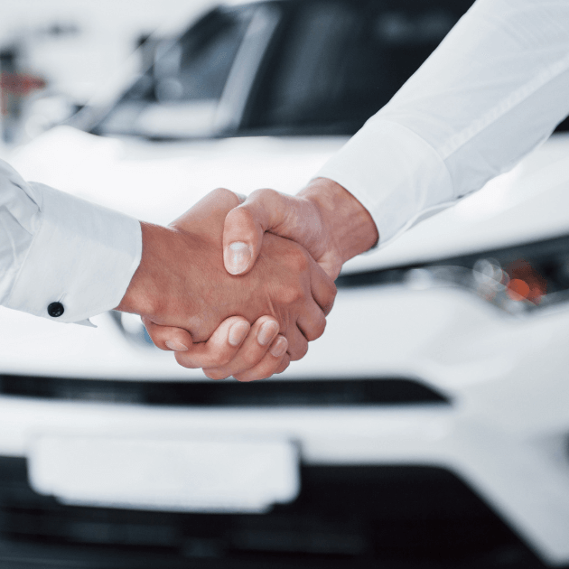 two people shaking hands after purchasing a used vehicle