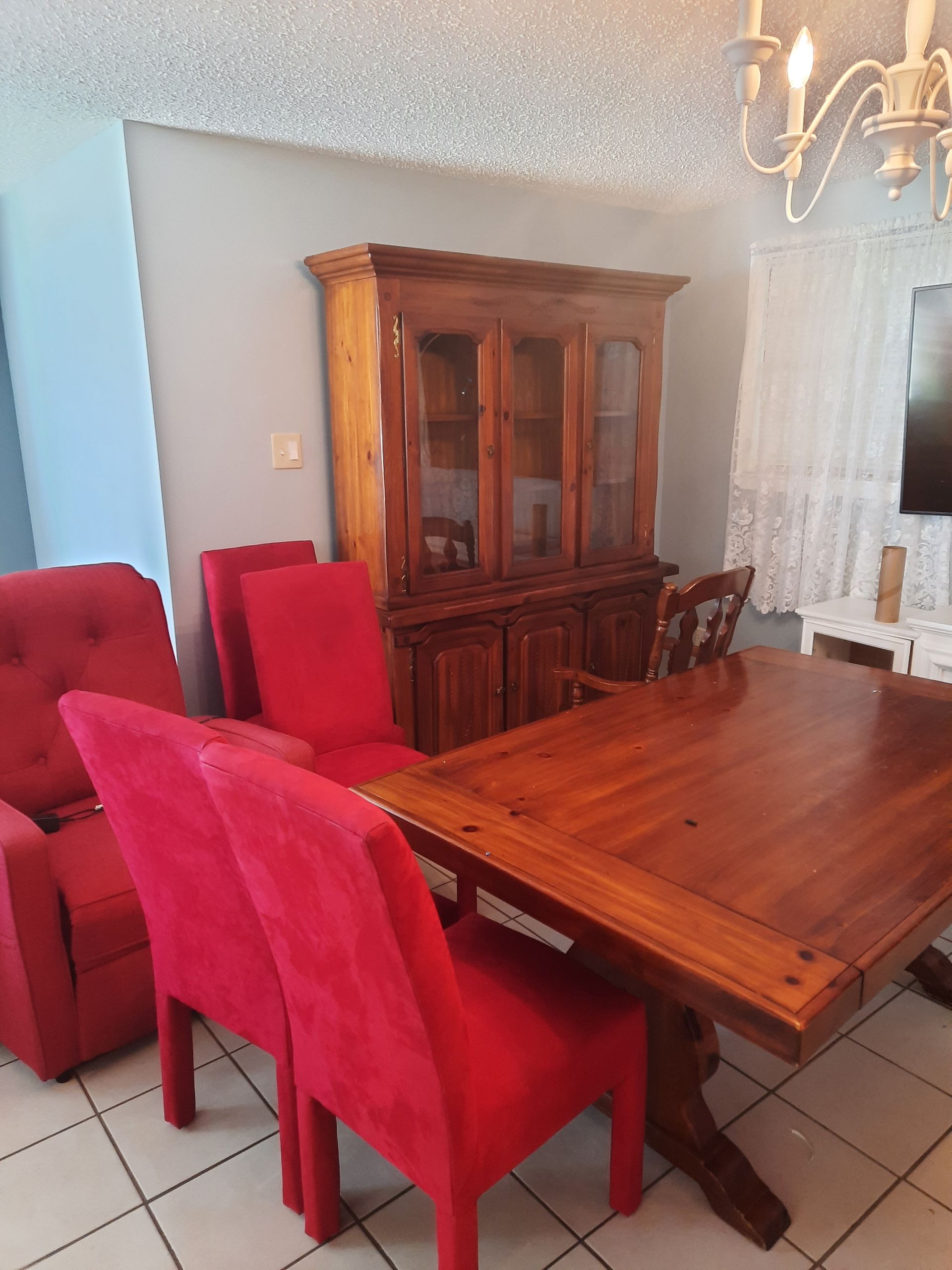 A living room with a wooden table and red chairs