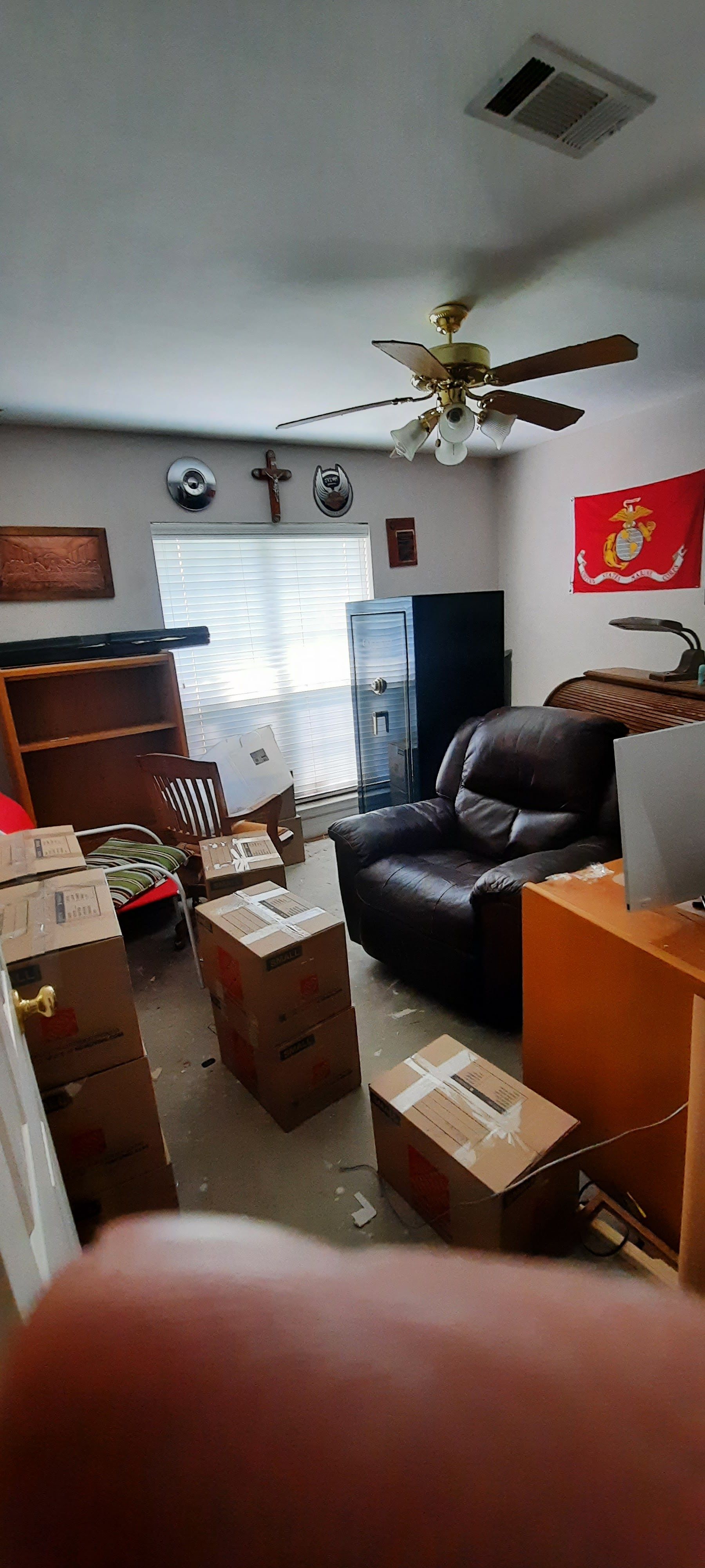 A living room filled with boxes and a ceiling fan.