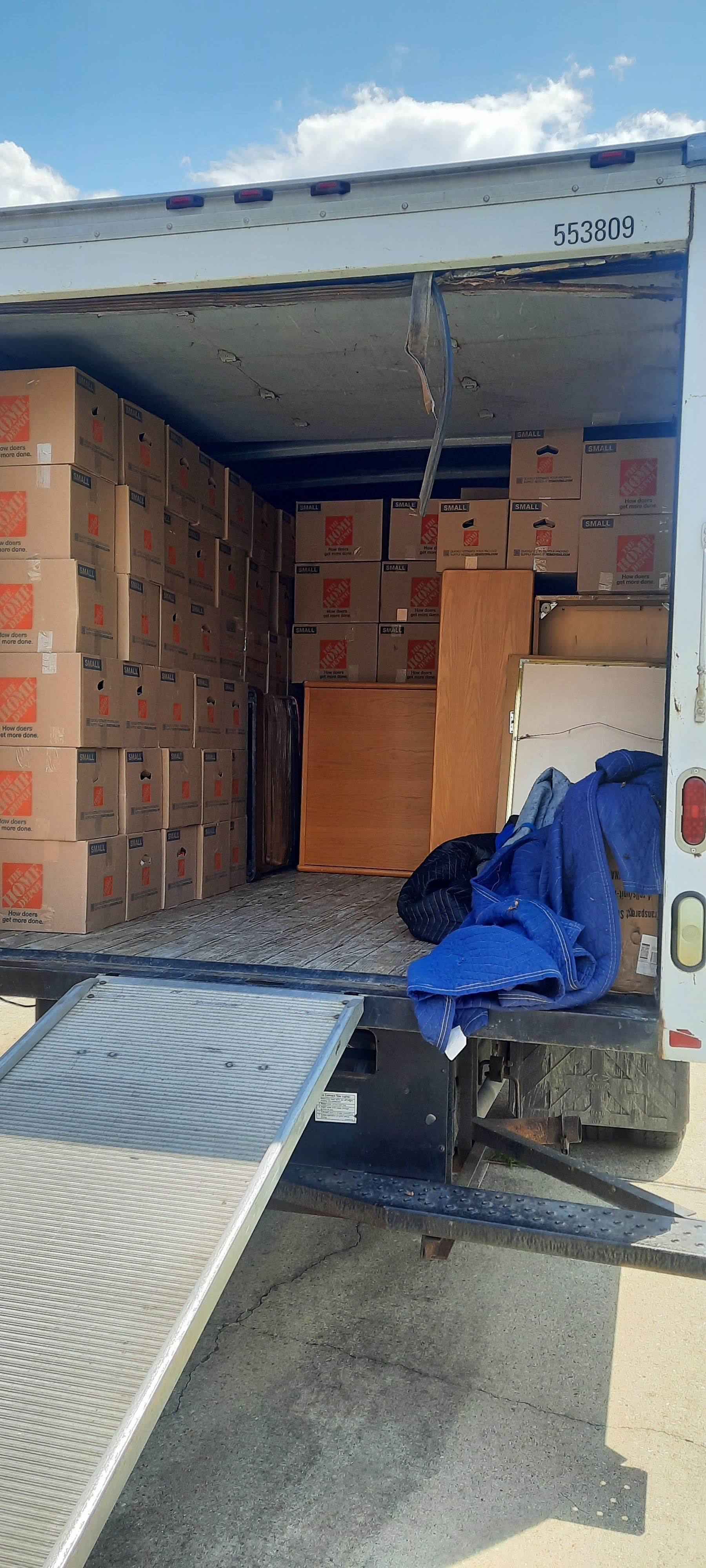 The back of a moving truck filled with boxes and a ramp.