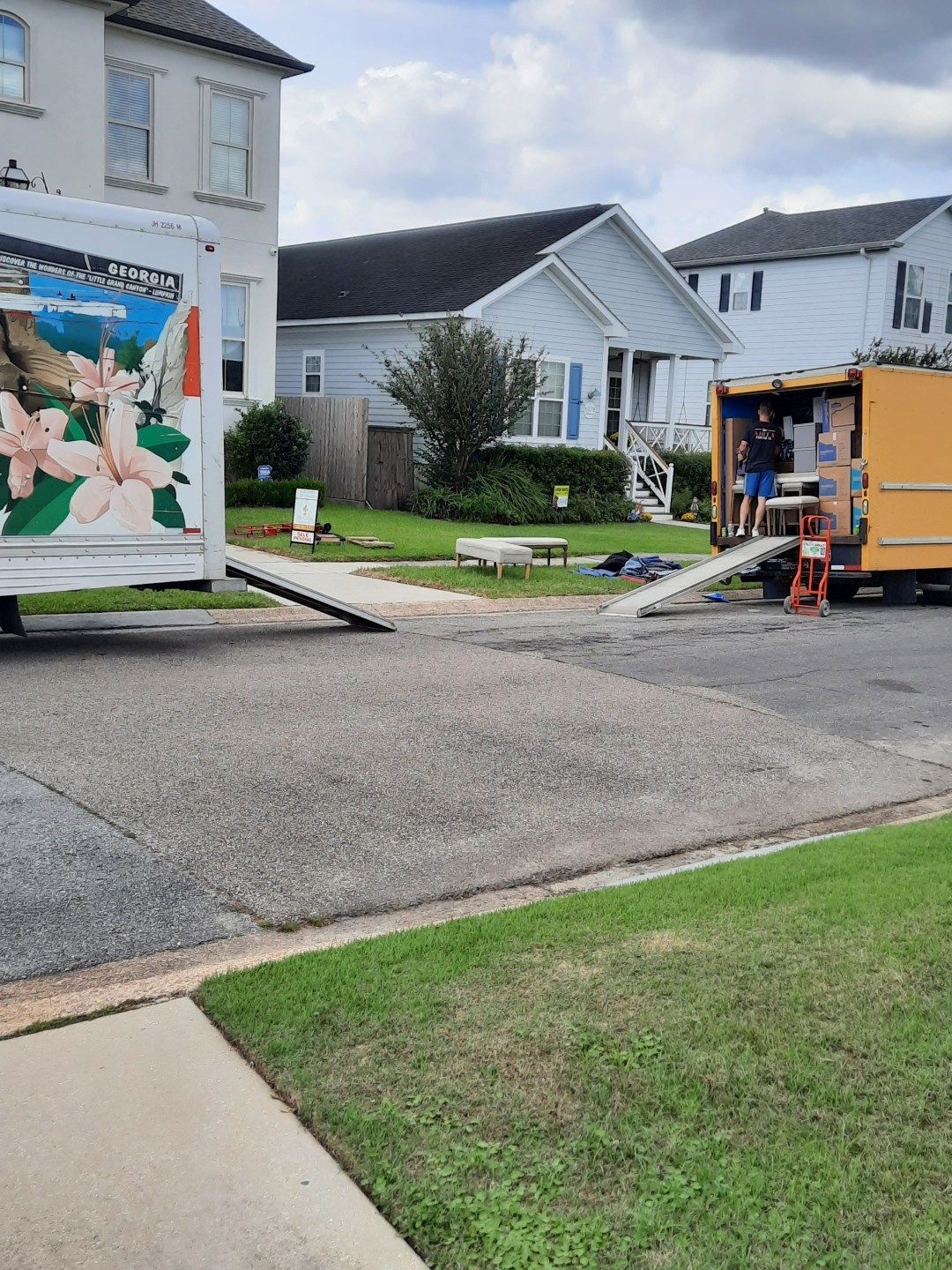 A moving truck is parked on the side of the road in front of a house.