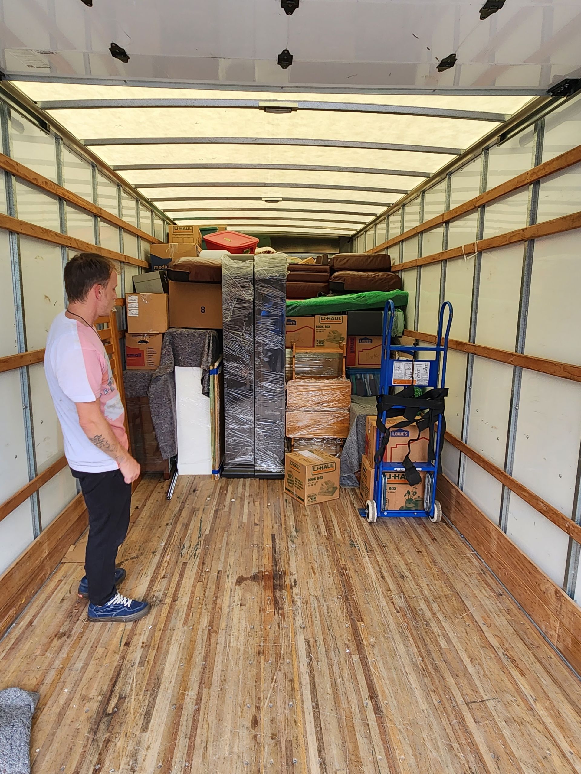 A man is standing in the back of a moving truck.