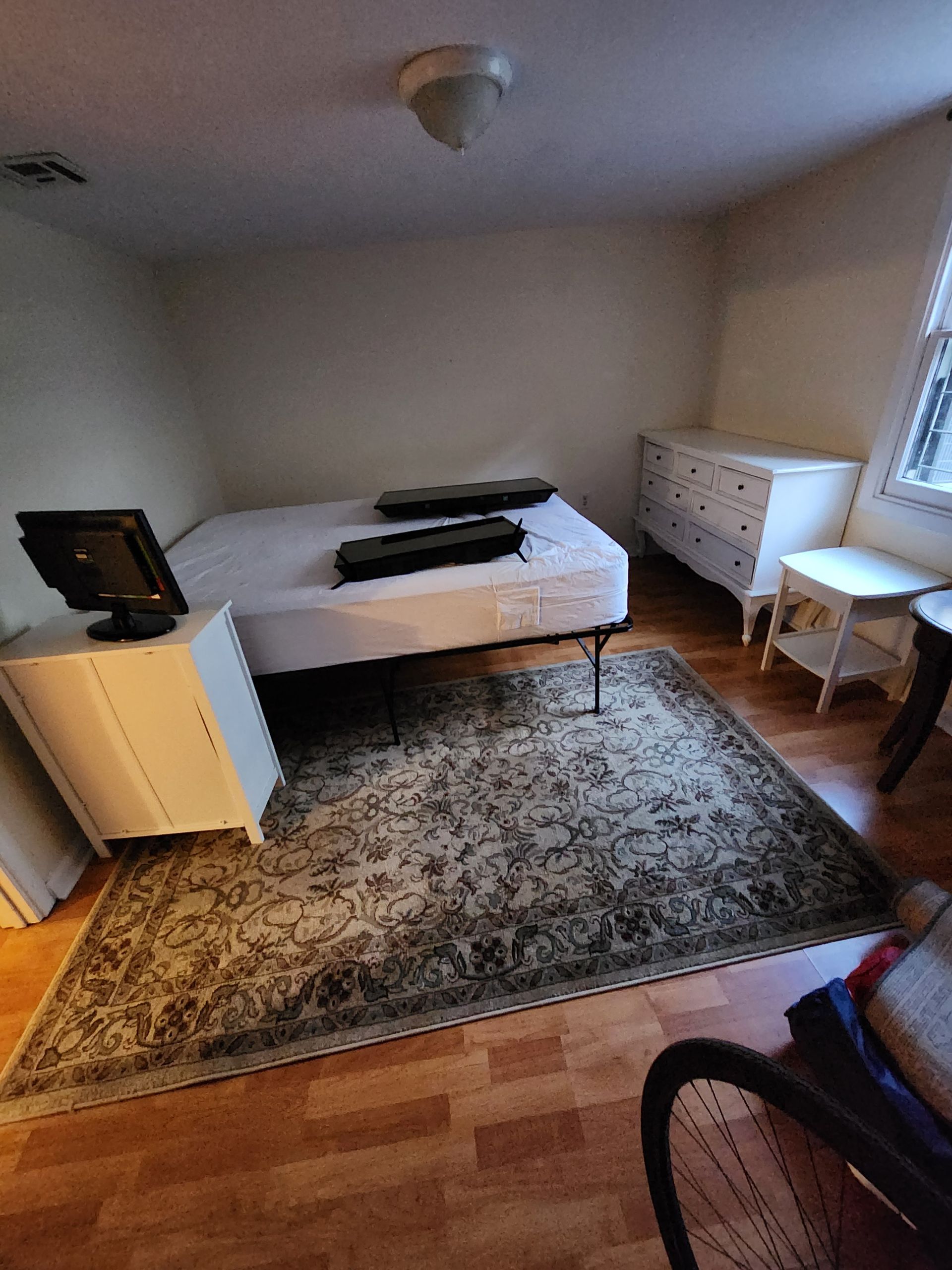 A bedroom with a bed , dresser , and rug.