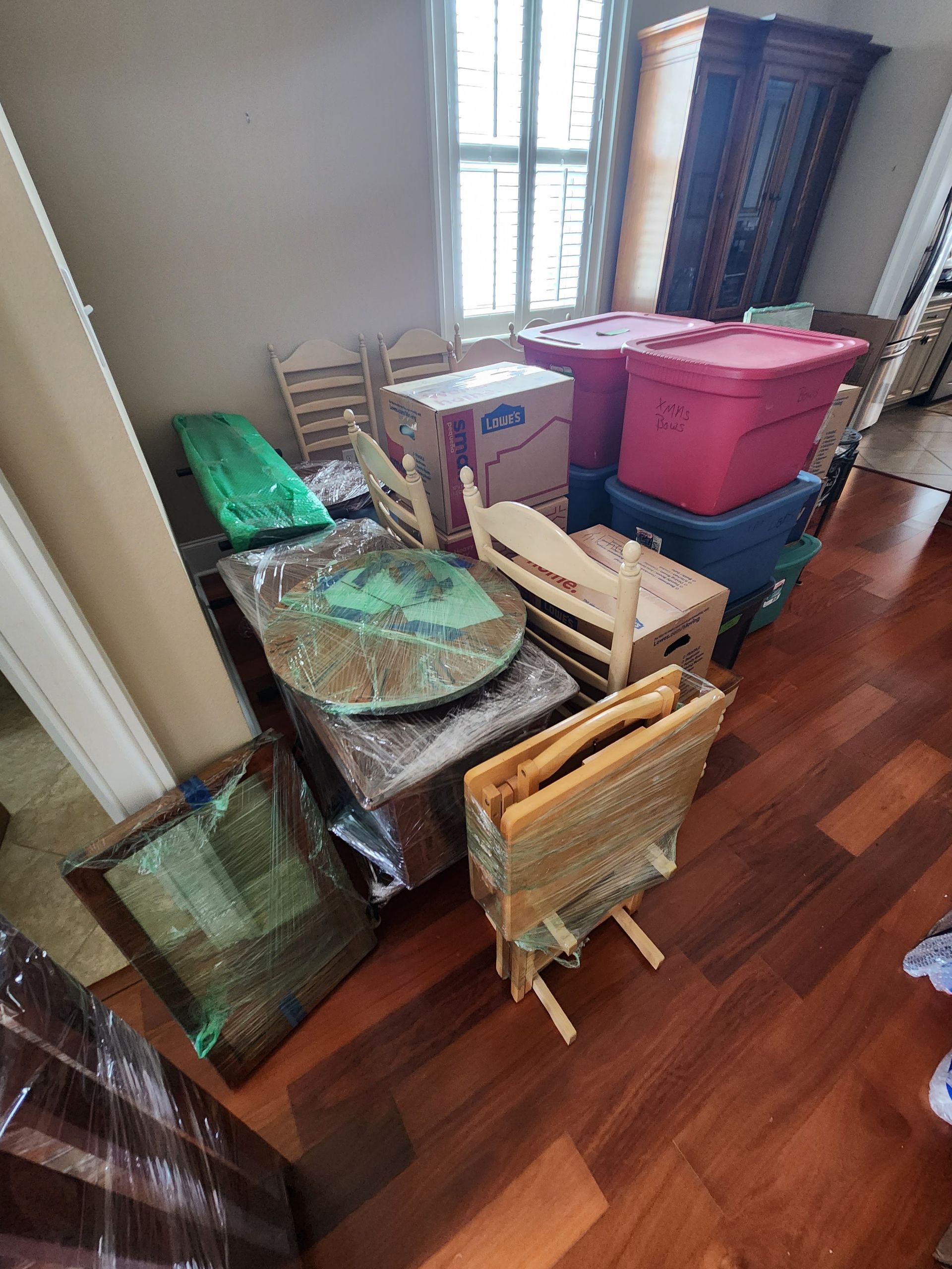 A room filled with boxes , chairs , a table and a window.