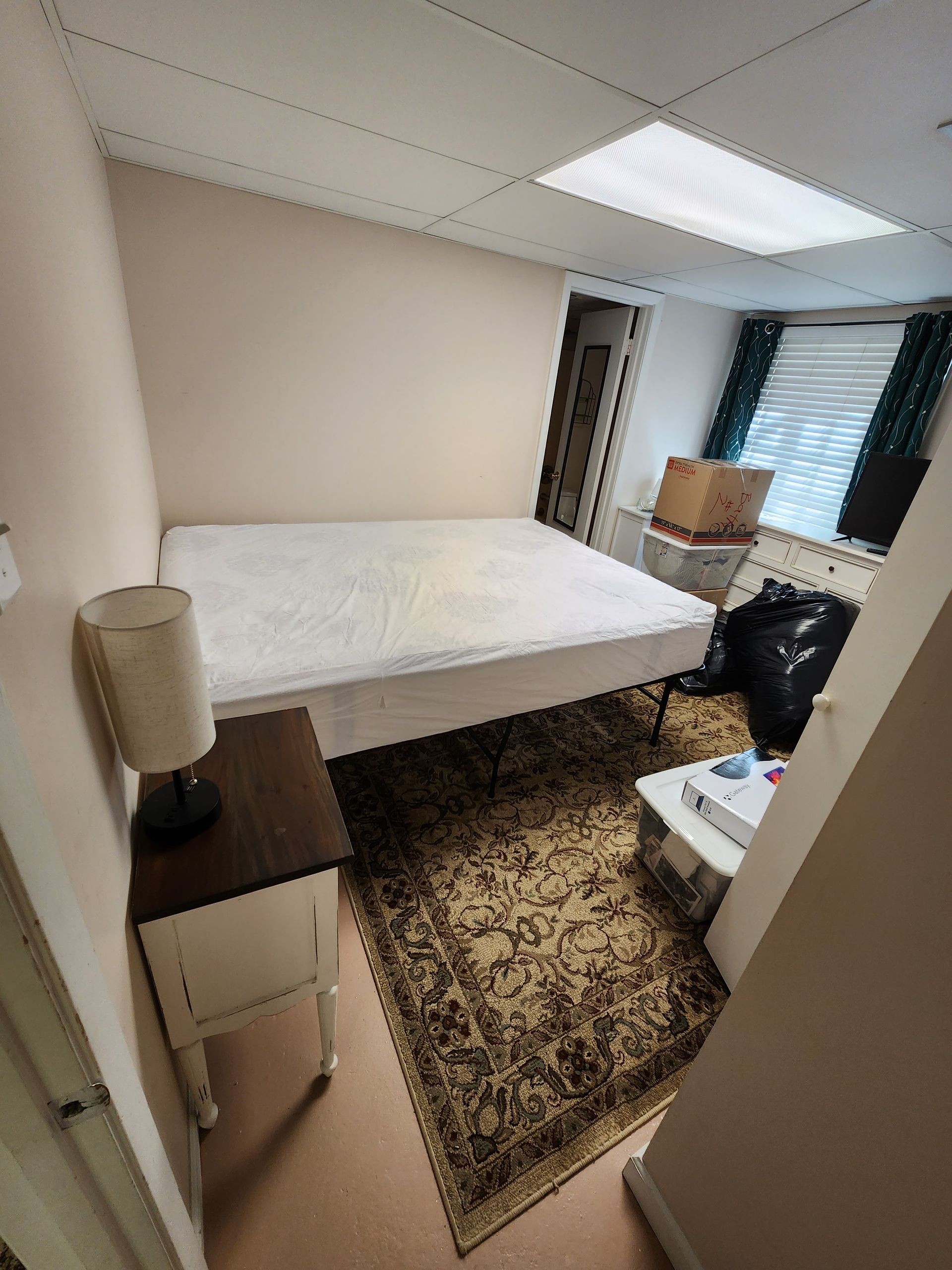 A bedroom with a bed , nightstand , lamp and rug.