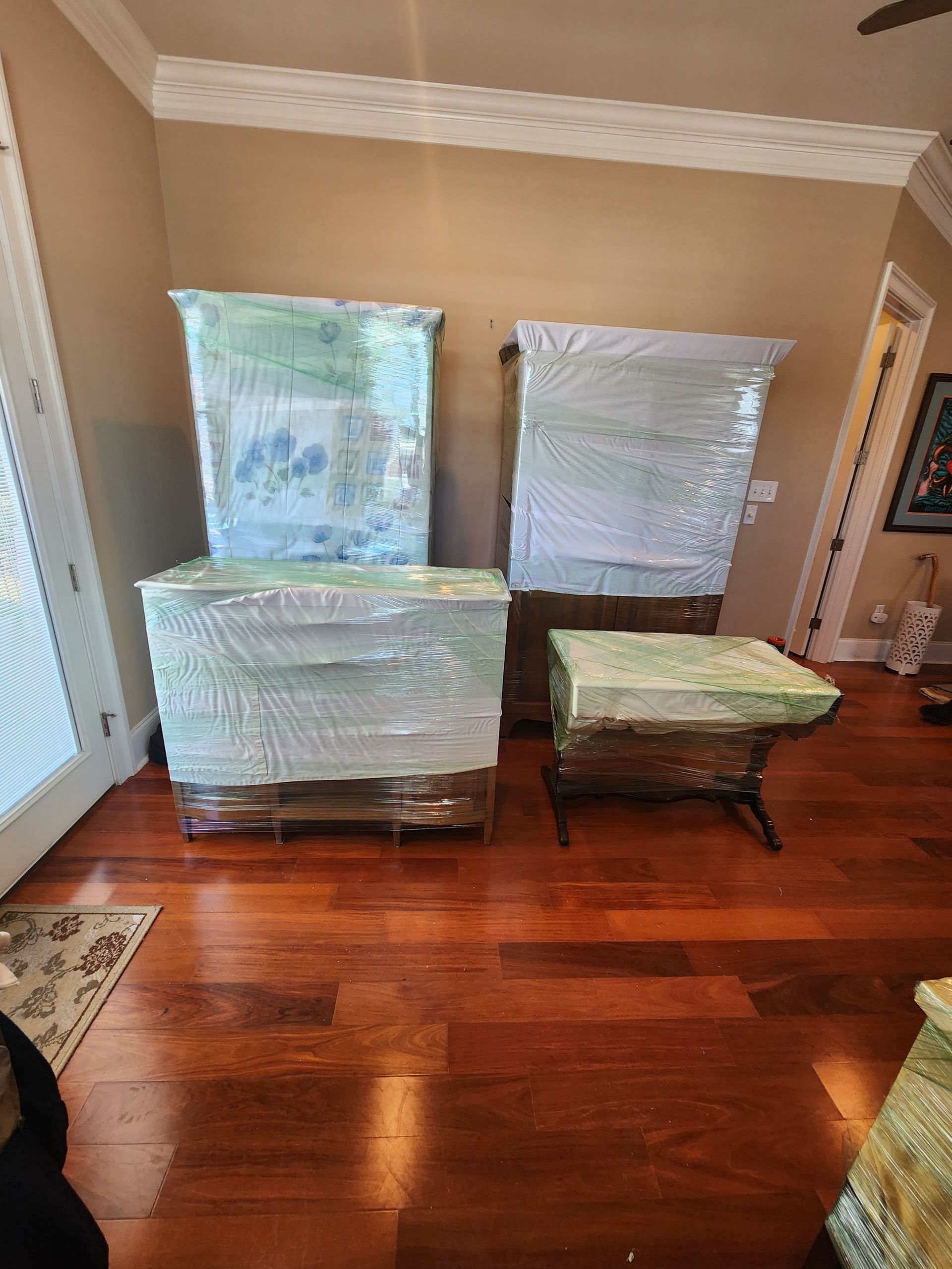A living room filled with furniture wrapped in plastic.