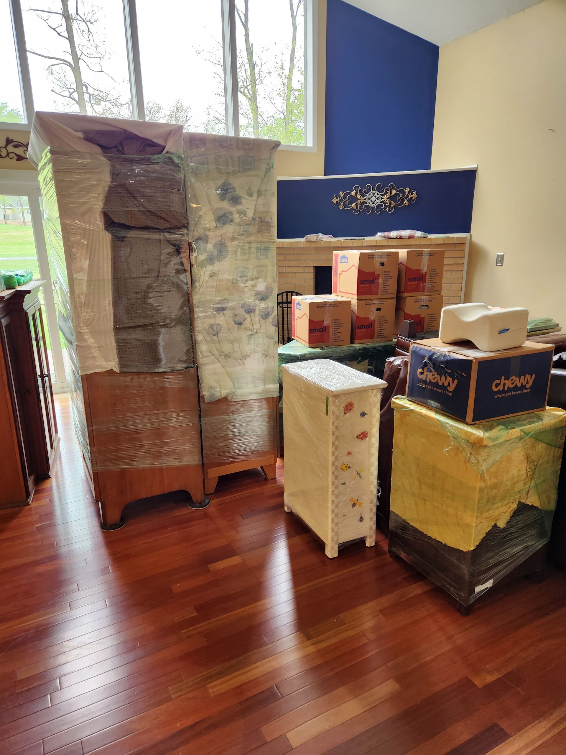 A living room filled with furniture and boxes wrapped in plastic.