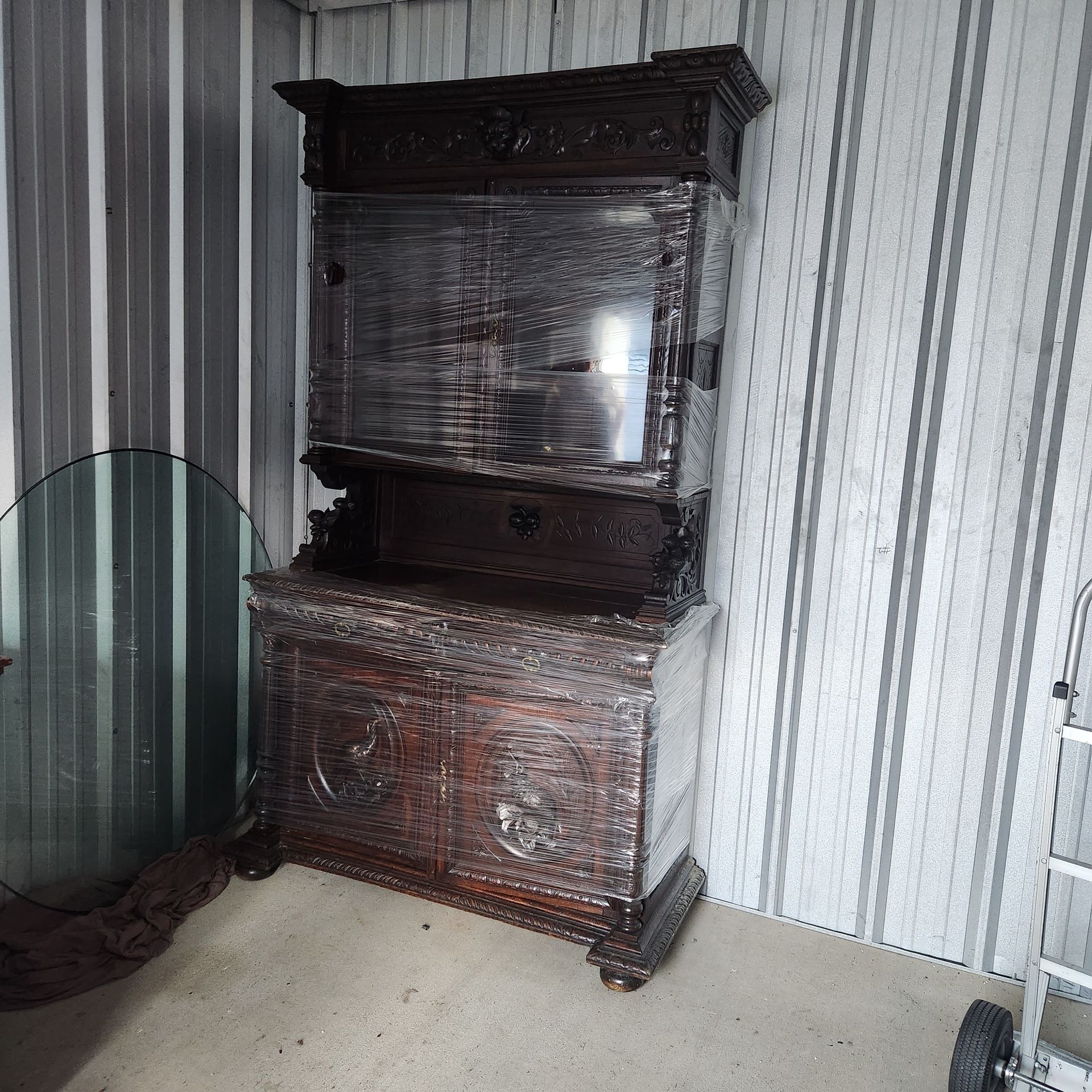 A wooden cabinet with a glass door sits in a room with striped wallpaper