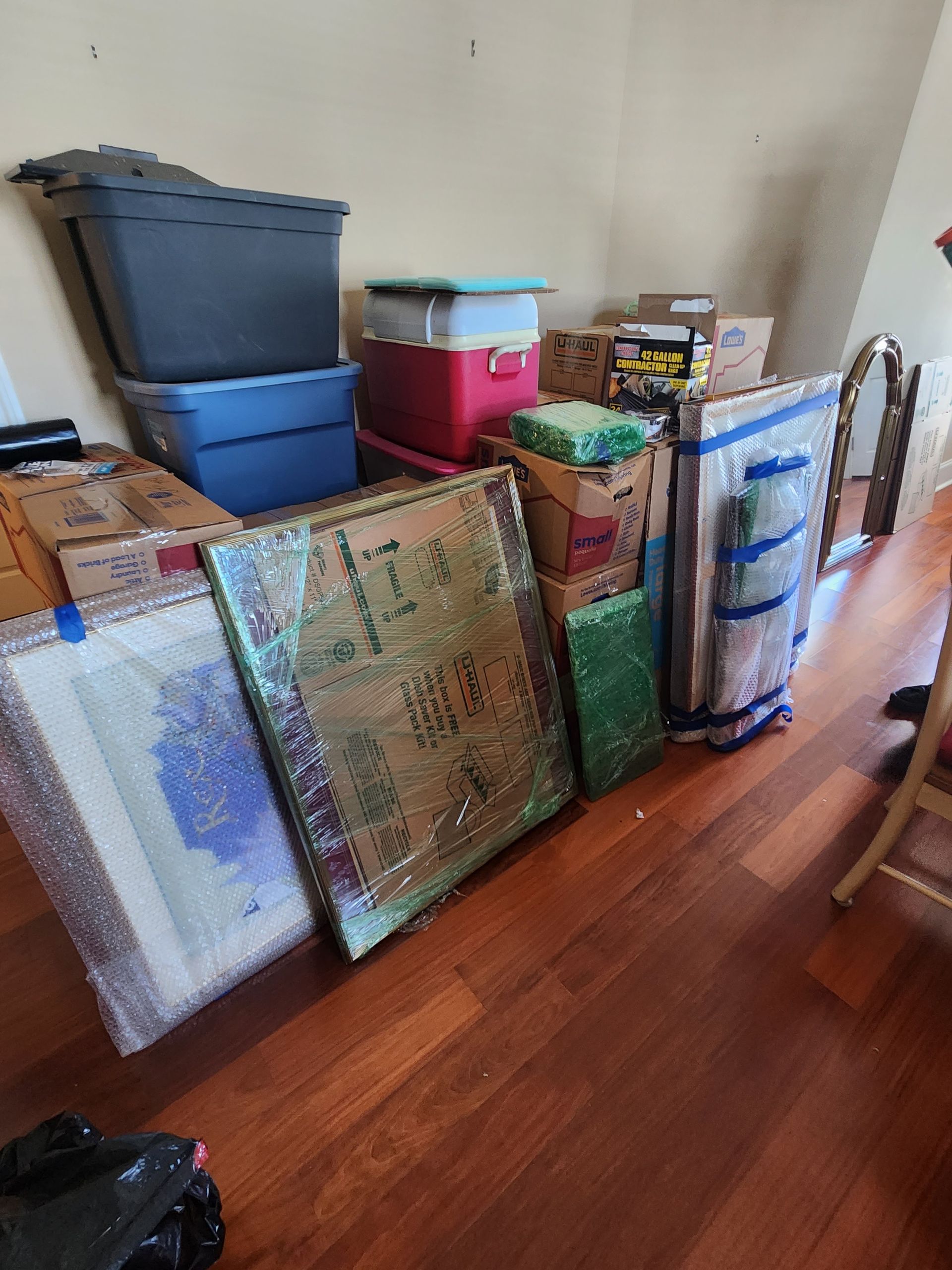 A room filled with boxes and paintings on the floor.