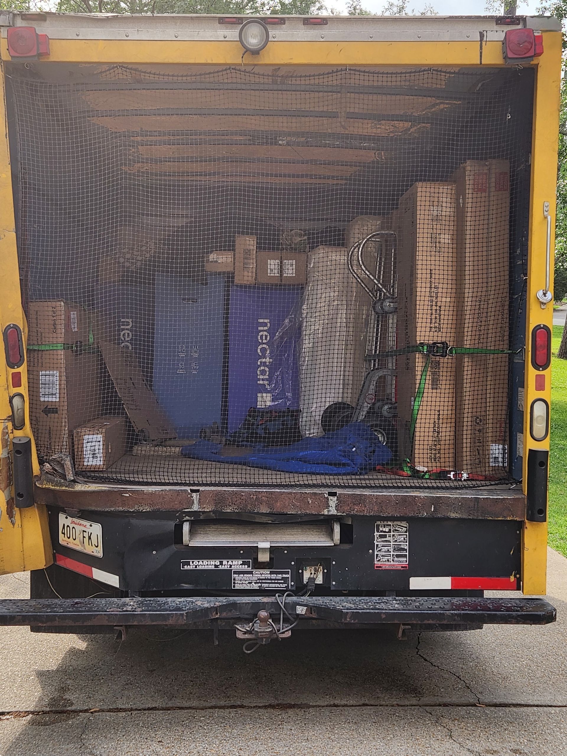 The back of a yellow delivery truck is filled with boxes.