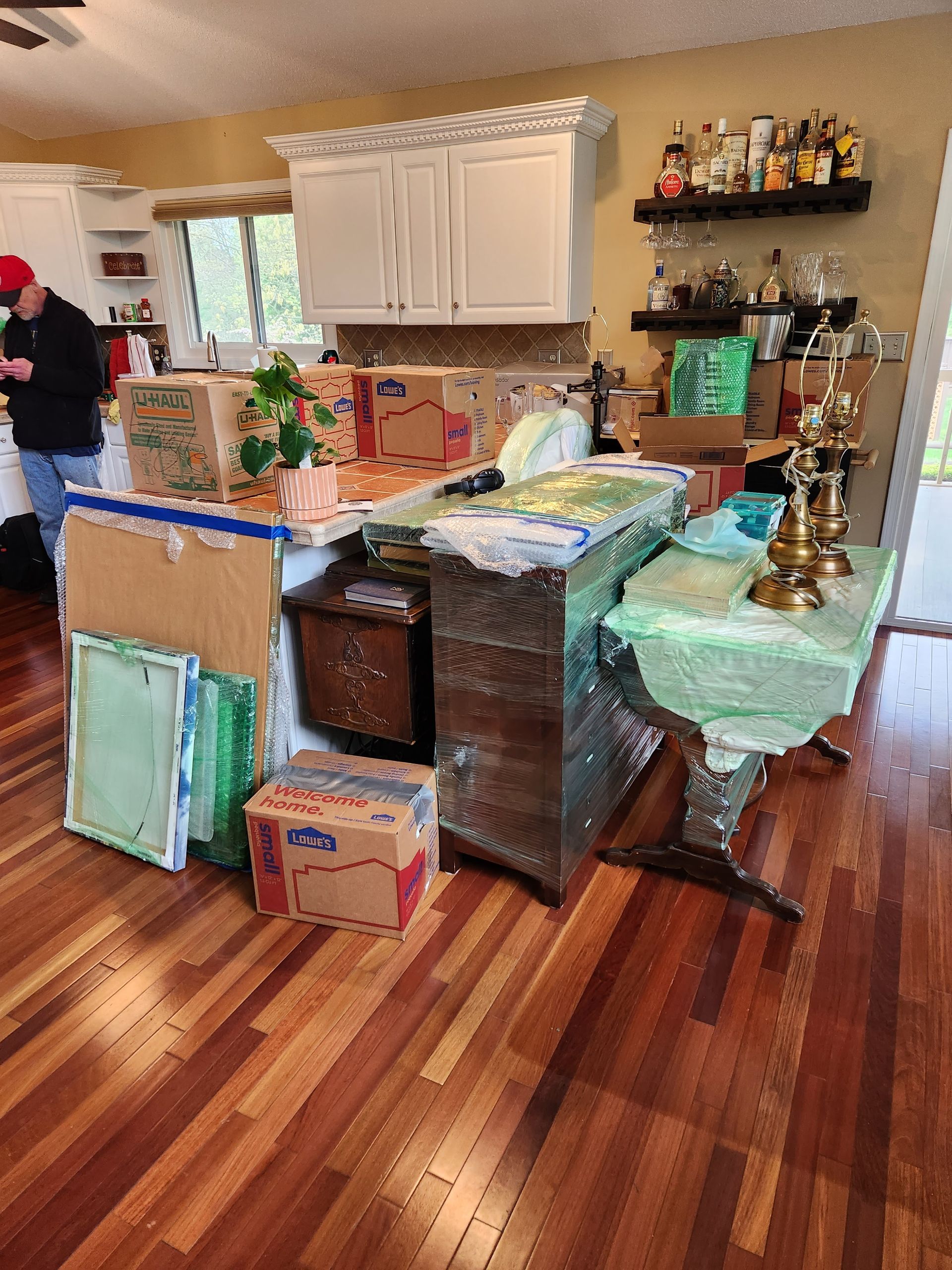 A man is standing in a kitchen filled with boxes and candles.