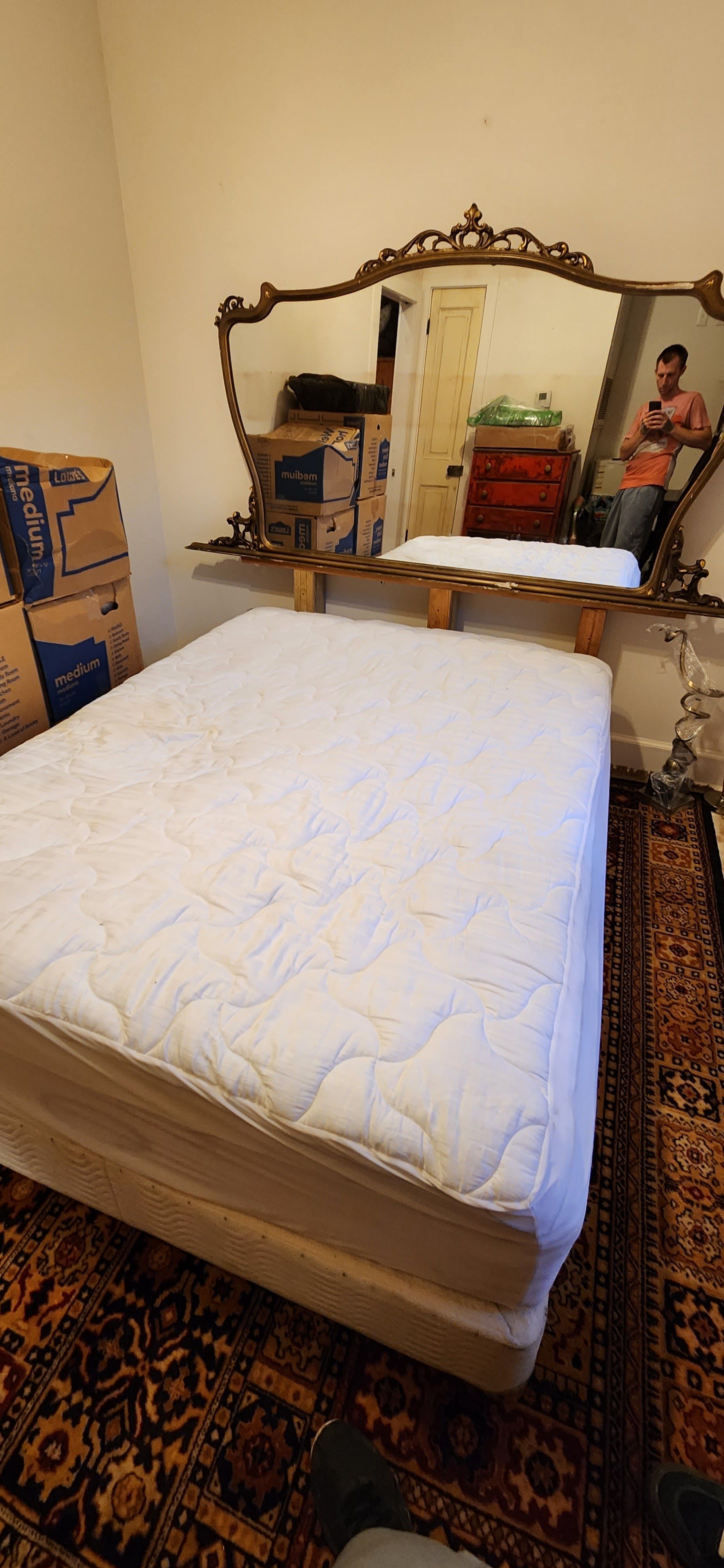 A bed with a mattress and a mirror in a bedroom.