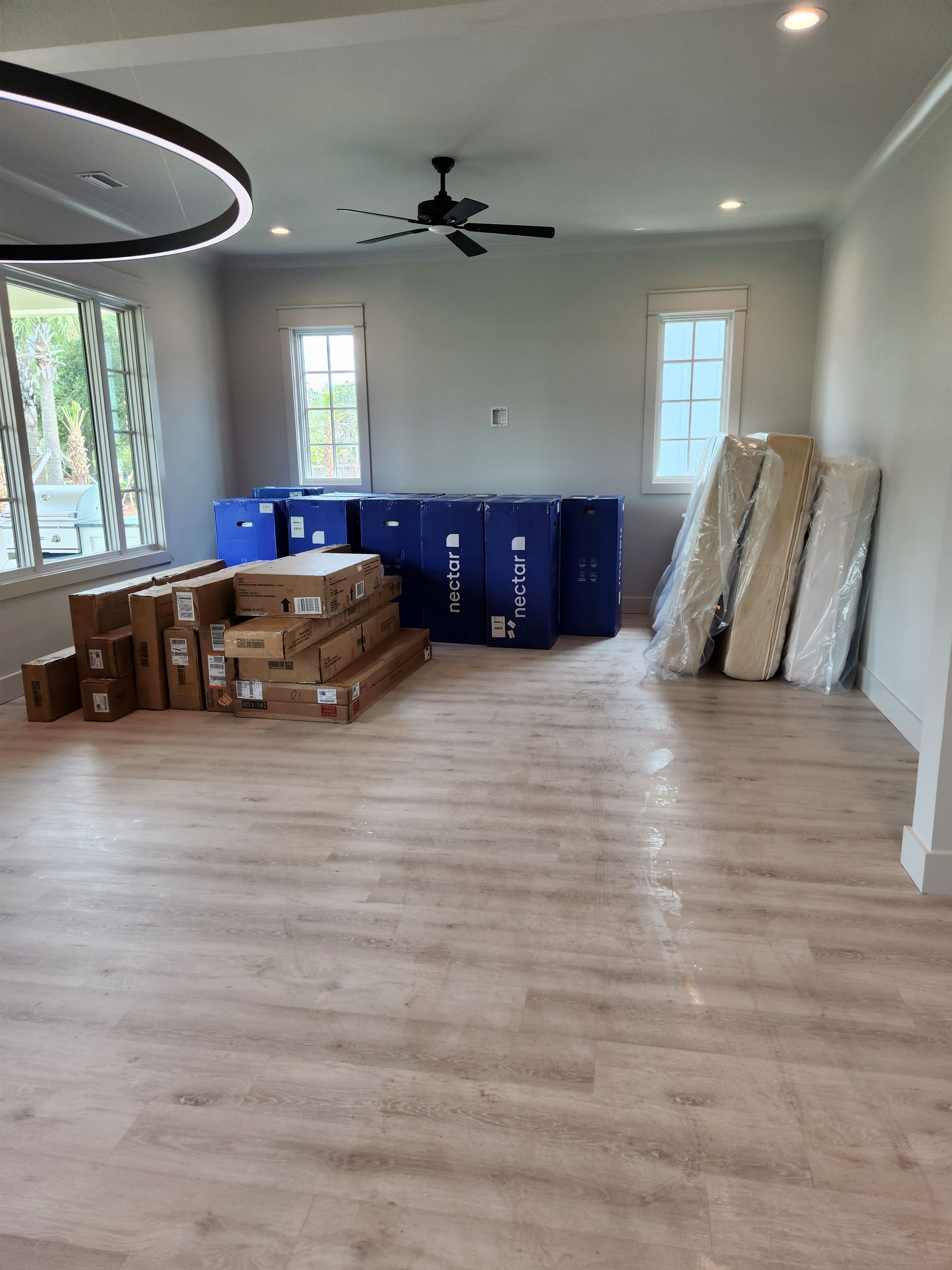 A living room filled with boxes and mattresses and a ceiling fan.