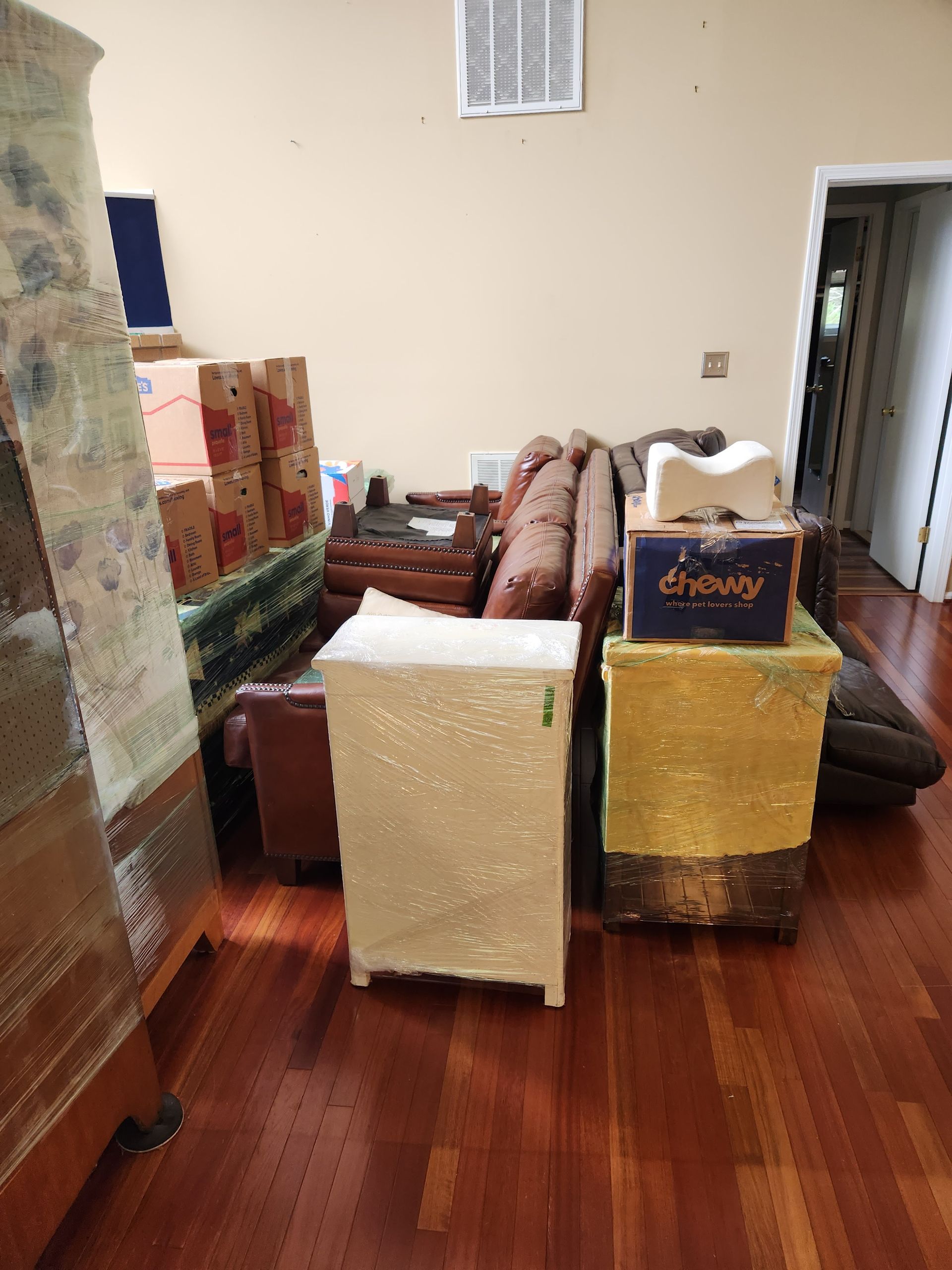 A living room filled with furniture and boxes wrapped in plastic.
