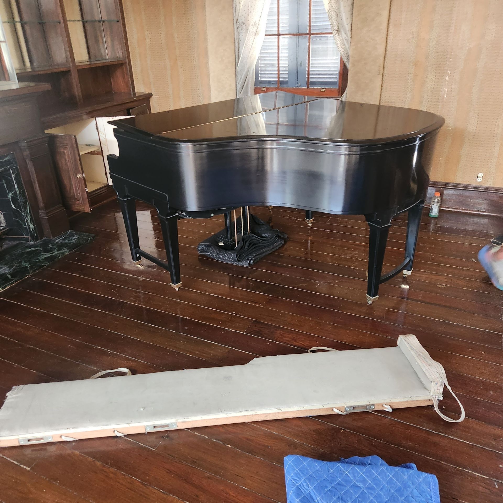 A piano is sitting on a wooden floor in a room
