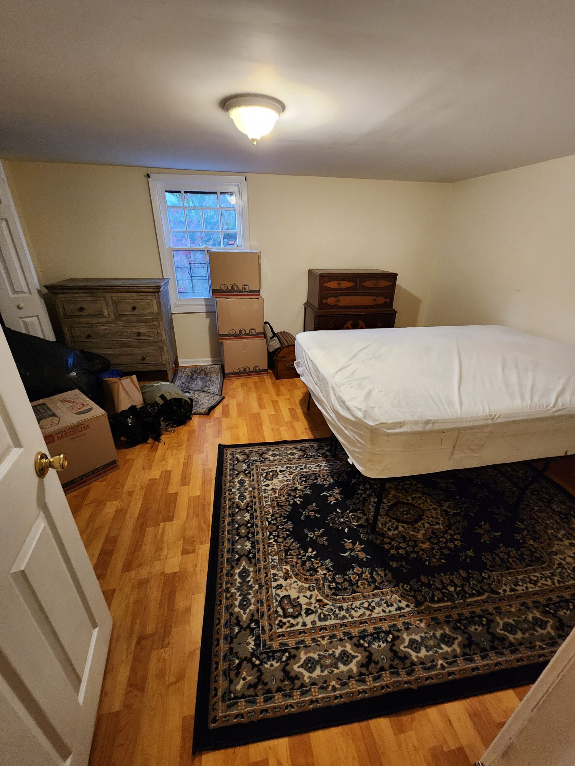 A bedroom with a bed and boxes on the floor