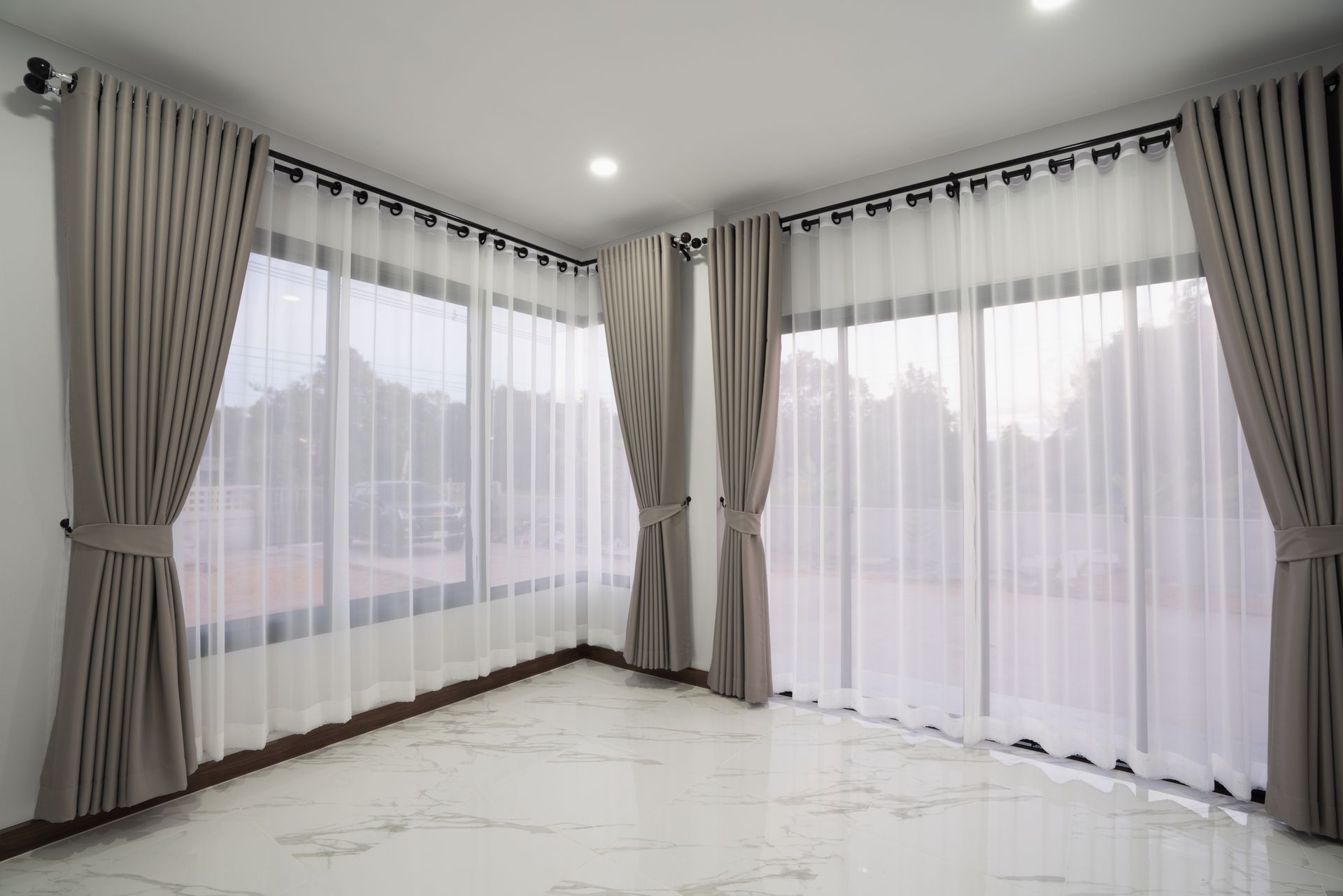 Custom window treatments in modern room with marble floors, vertical blinds, and large windows.