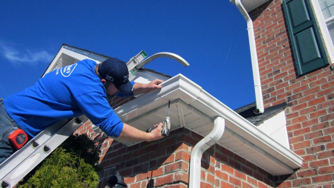 Man in ladder installing gutter — Savannah, GA — Professional Grade Gutters