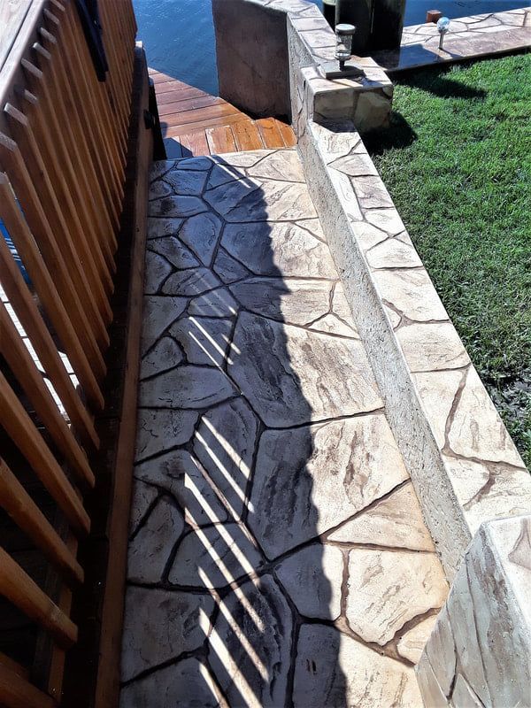 A concrete walkway leading to a dock with a wooden railing