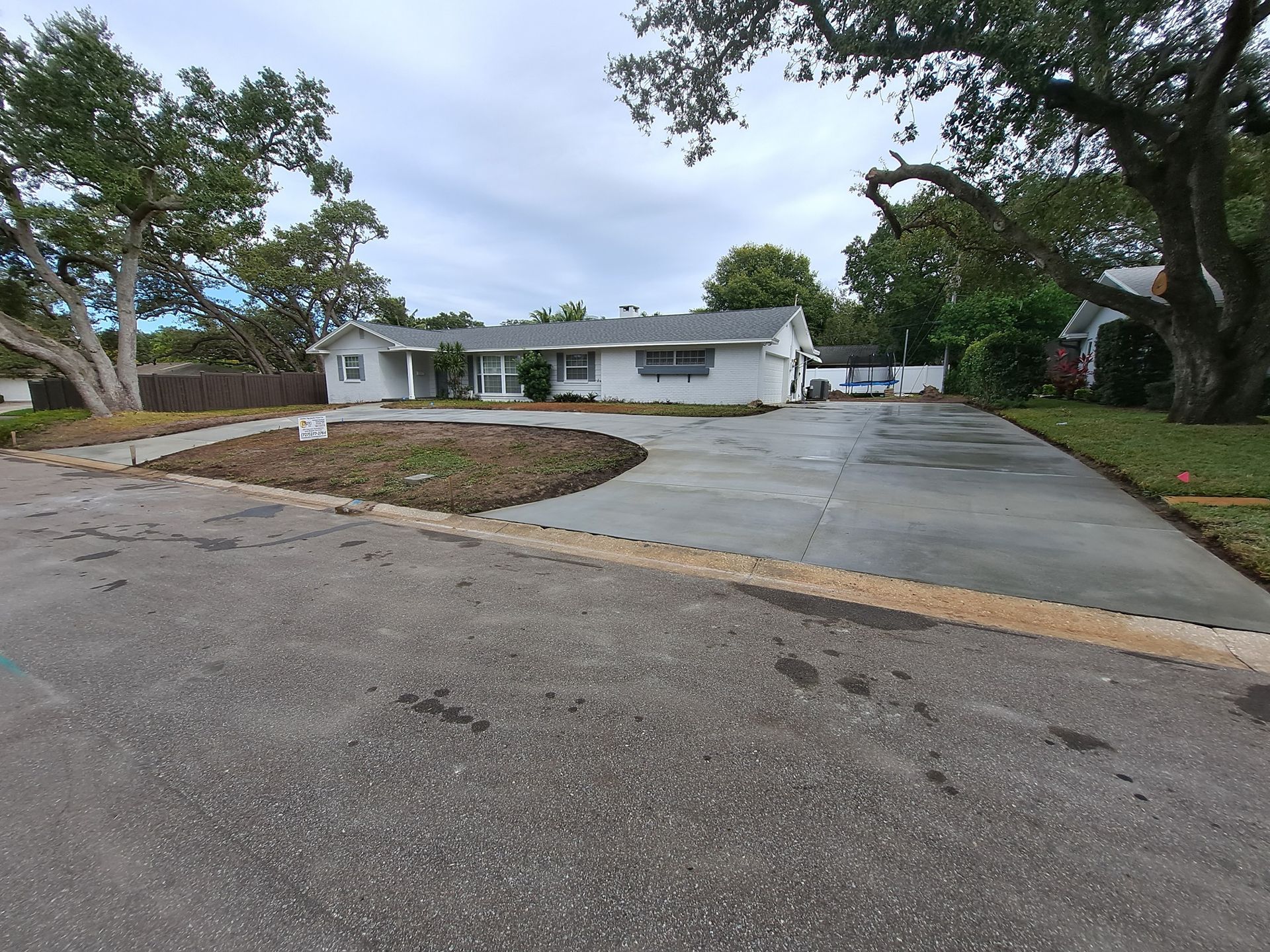 A white house with a concrete driveway in front of it
