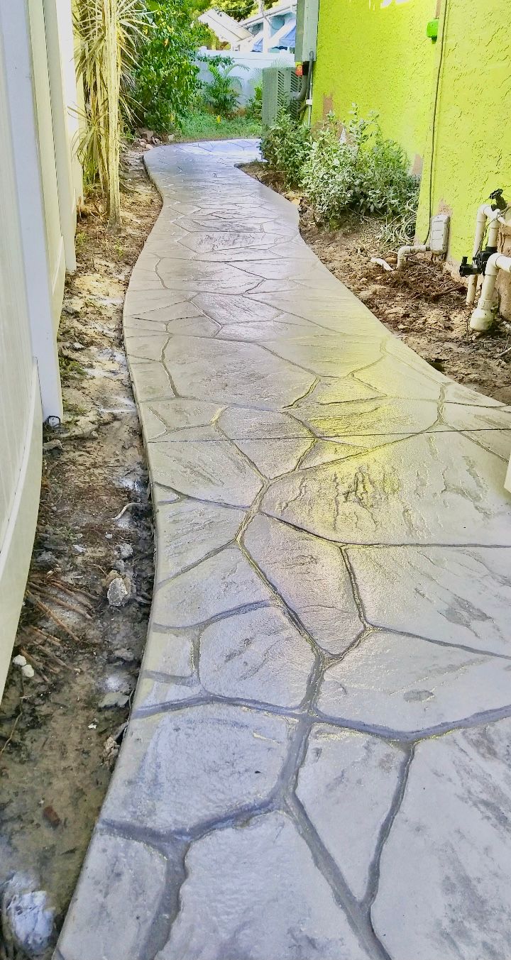 A concrete walkway leading to a yellow fence.
