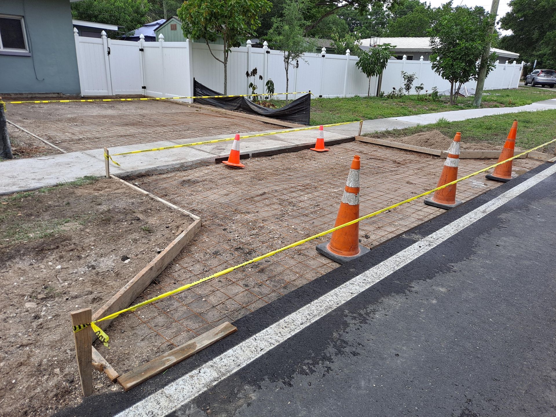 A construction site with a fence and cones on the side of the road.