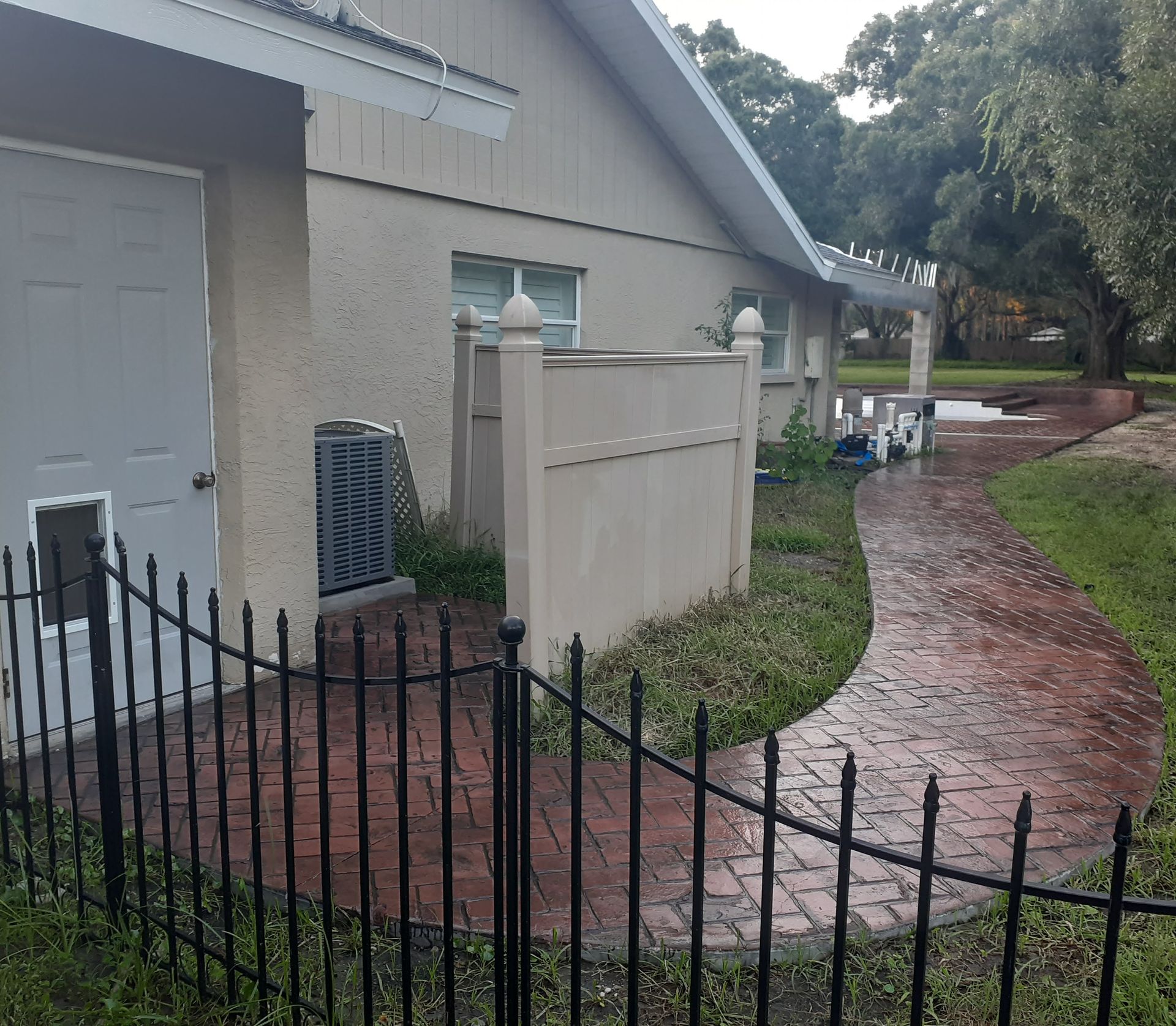 A wrought iron fence surrounds a walkway leading to a house