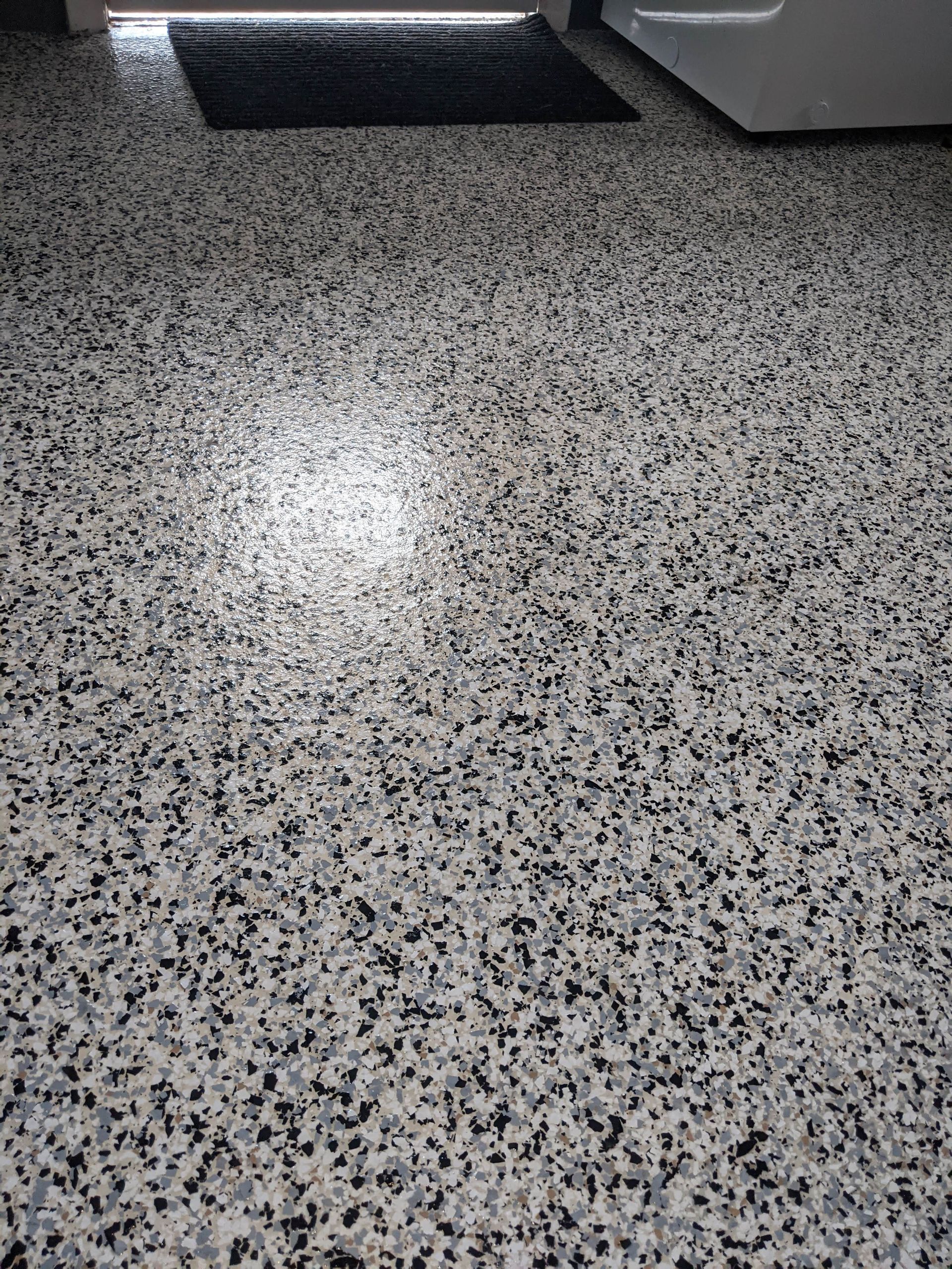 A close up of a gray and black floor in a laundry room.
