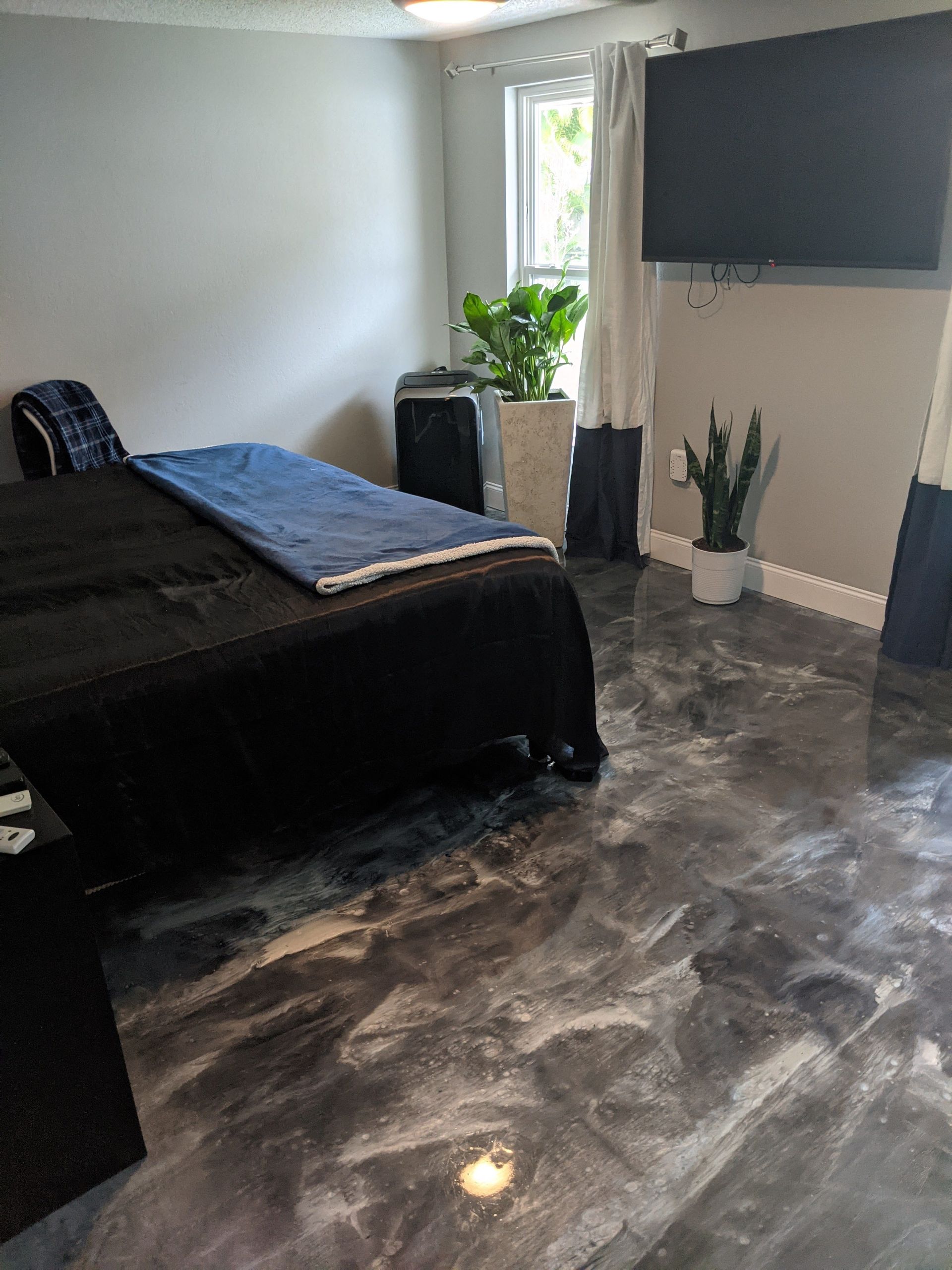 A bedroom with a bed and a television on the wall.